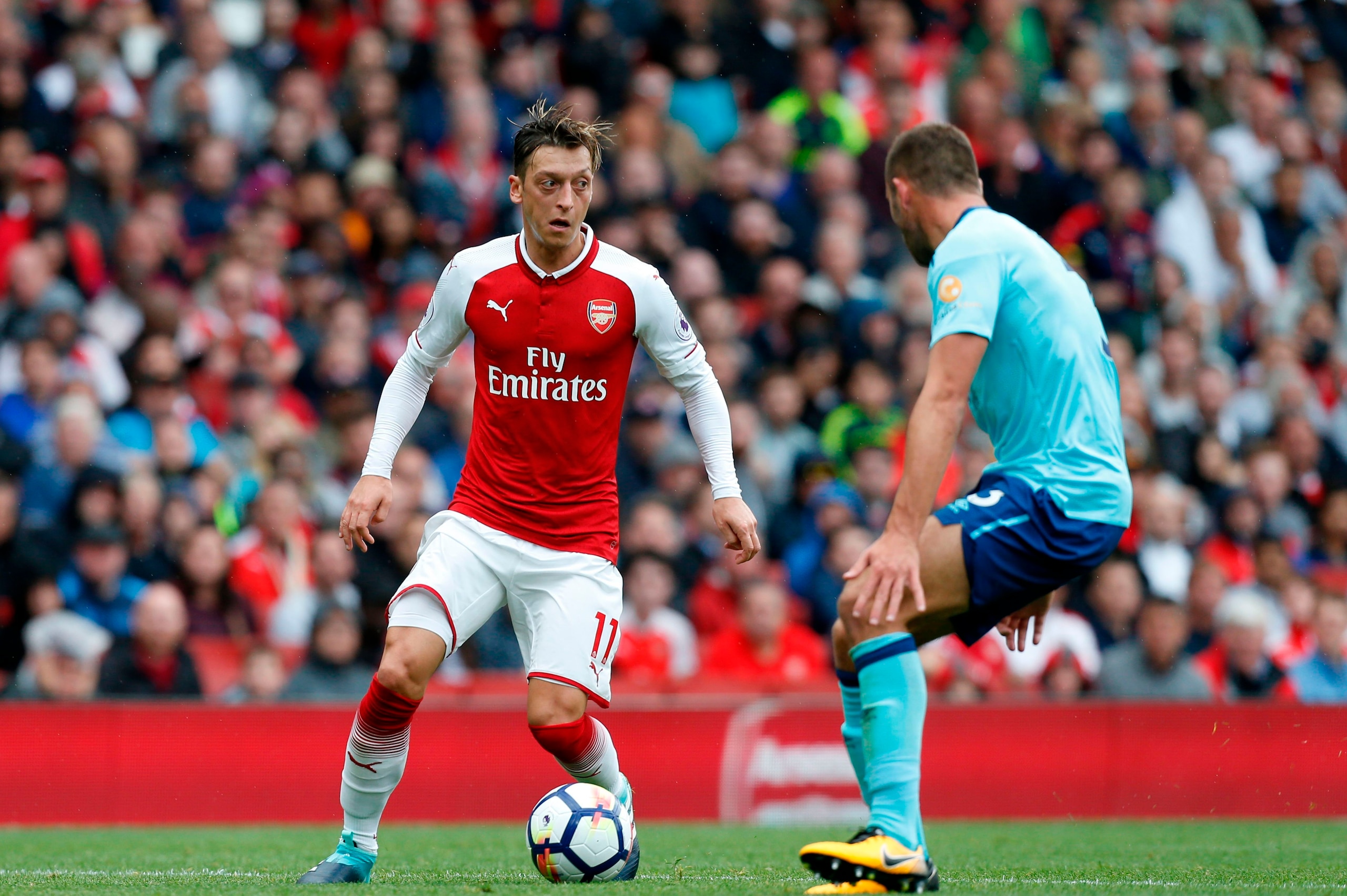 Arsenal's German midfielder Mesut Ozil (L) takes on Bournemouth's English defender Steve Cook (R) during the English Premier League football match between Arsenal and Bournemouth at the Emirates Stadium in London on September 9, 2017. / AFP PHOTO / Ian KI