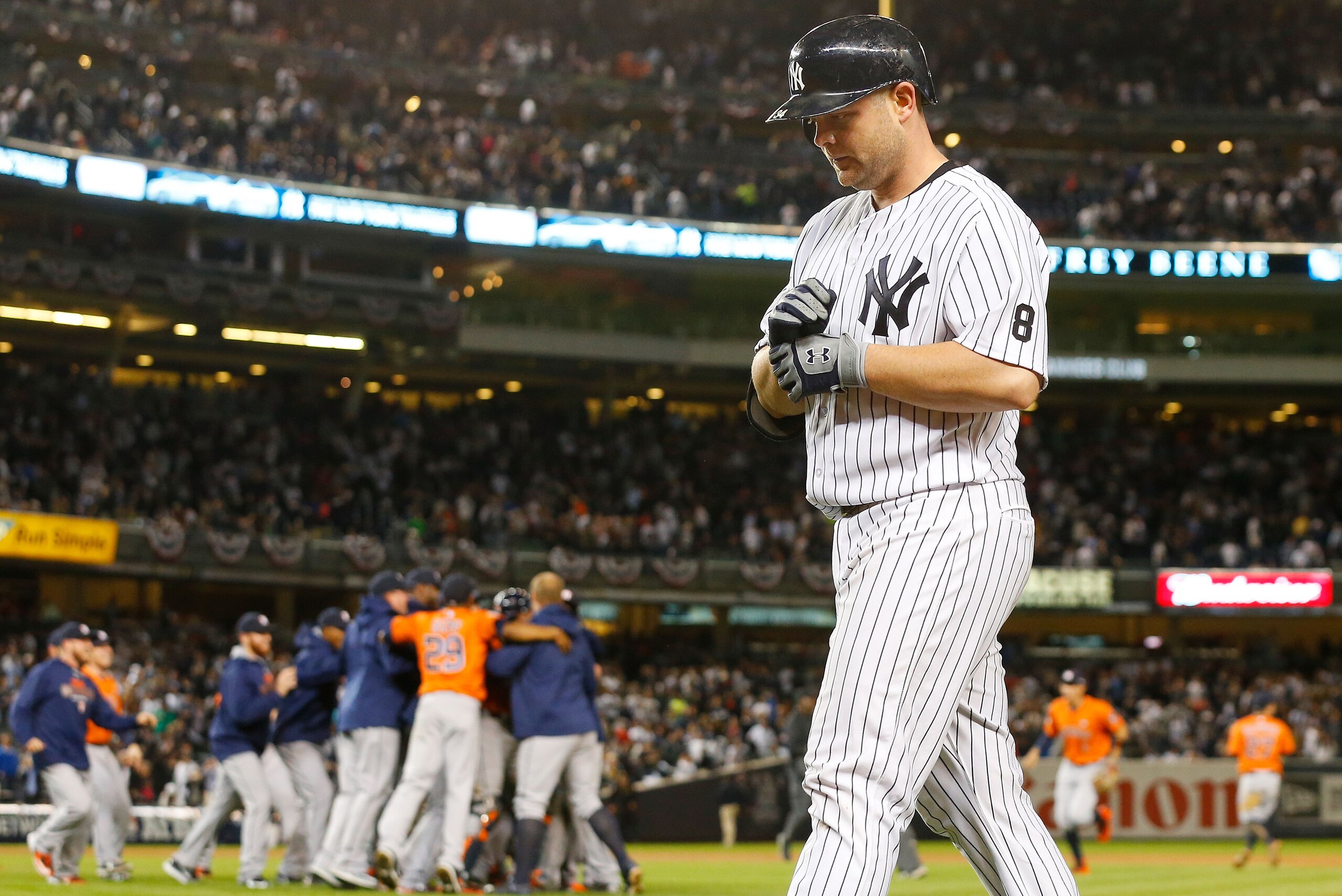 NEW YORK, NY - OCTOBER 06:  (NEW YORK DAILIES OUT)  Brian McCann #34 of the New York Yankees walks off the field after grounding out to end the American League Wild Card Game as the Houston Astros celebrate at Yankee Stadium on October 6, 2015 in the Bron