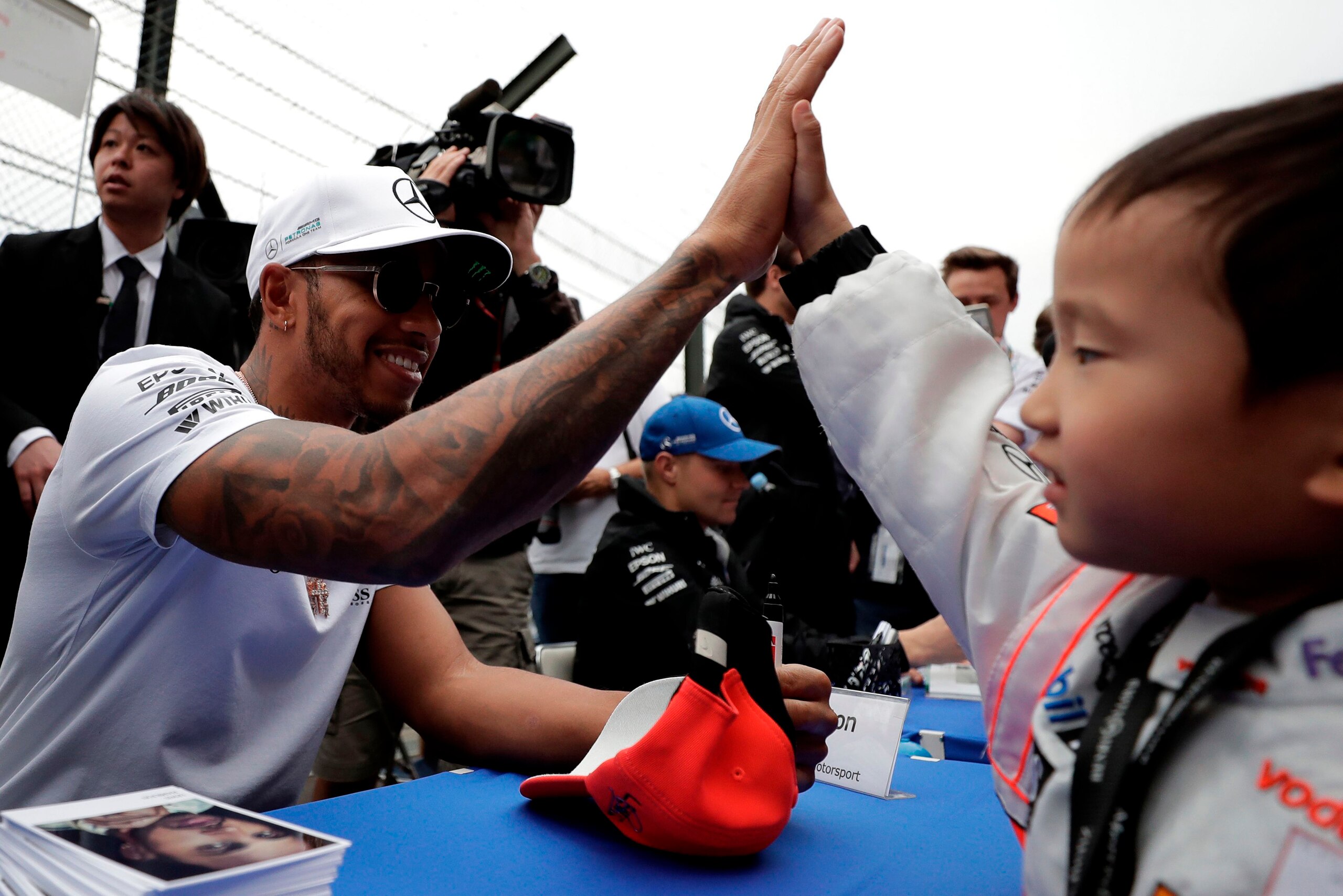 Mercedes' British driver Lewis Hamilton (L) gives a high five to a young boy during the autograph session of the Formula One Japanese Grand Prix at Suzuka circuit on October 5, 2017. / AFP PHOTO / Kiyoshi OTA        (Photo credit should read KIYOSHI OTA/A