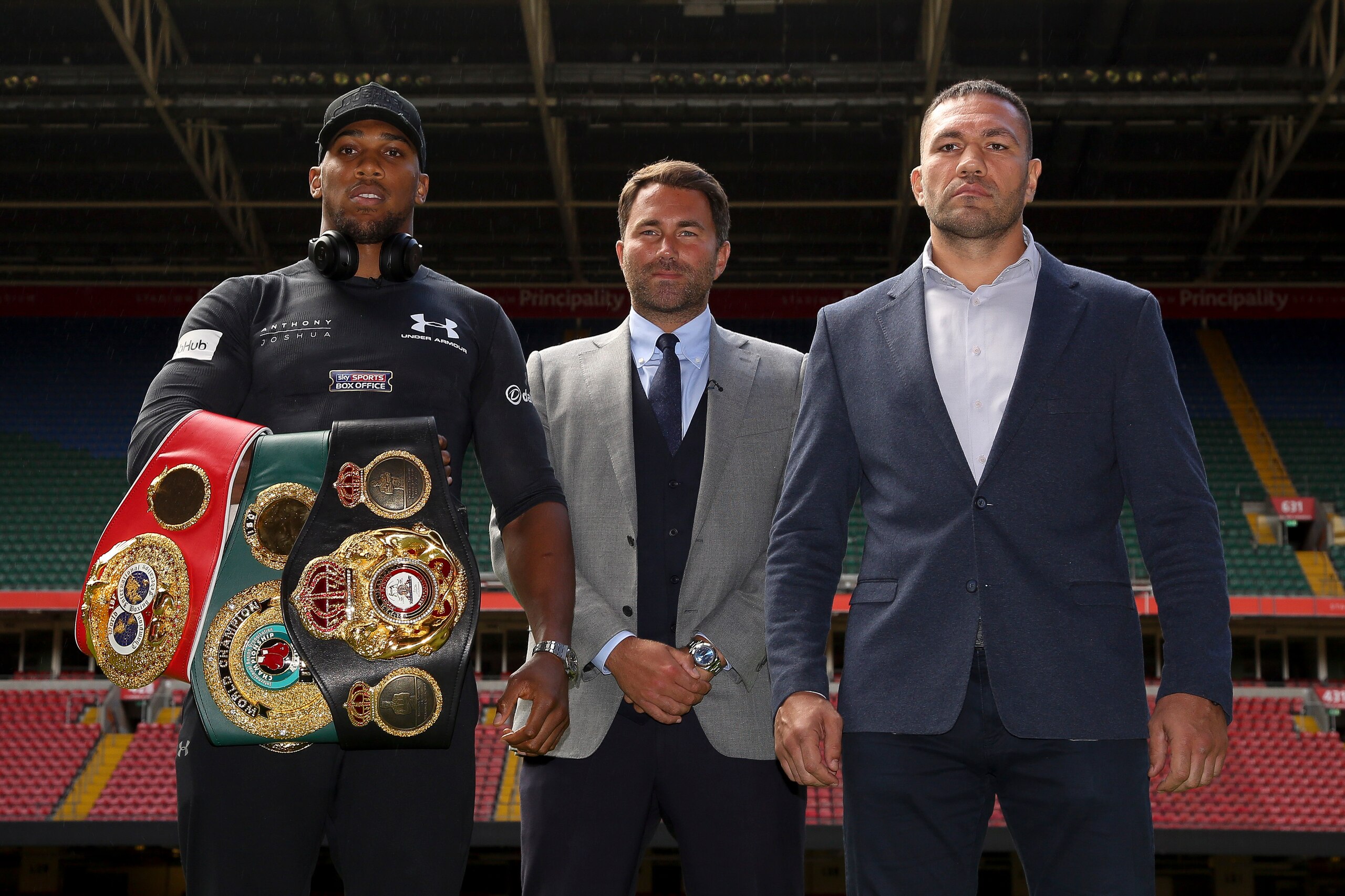 Britain's Anthony Joshua (L), boxing promoter Eddie Hearn (C) and Bulgaria's Kubrat Pulev (R) pose on the pitch at the Principality Stadium in Cardiff on September 11, 2017 during a promotional event for their heavyweight world title boxing match. 
Britai