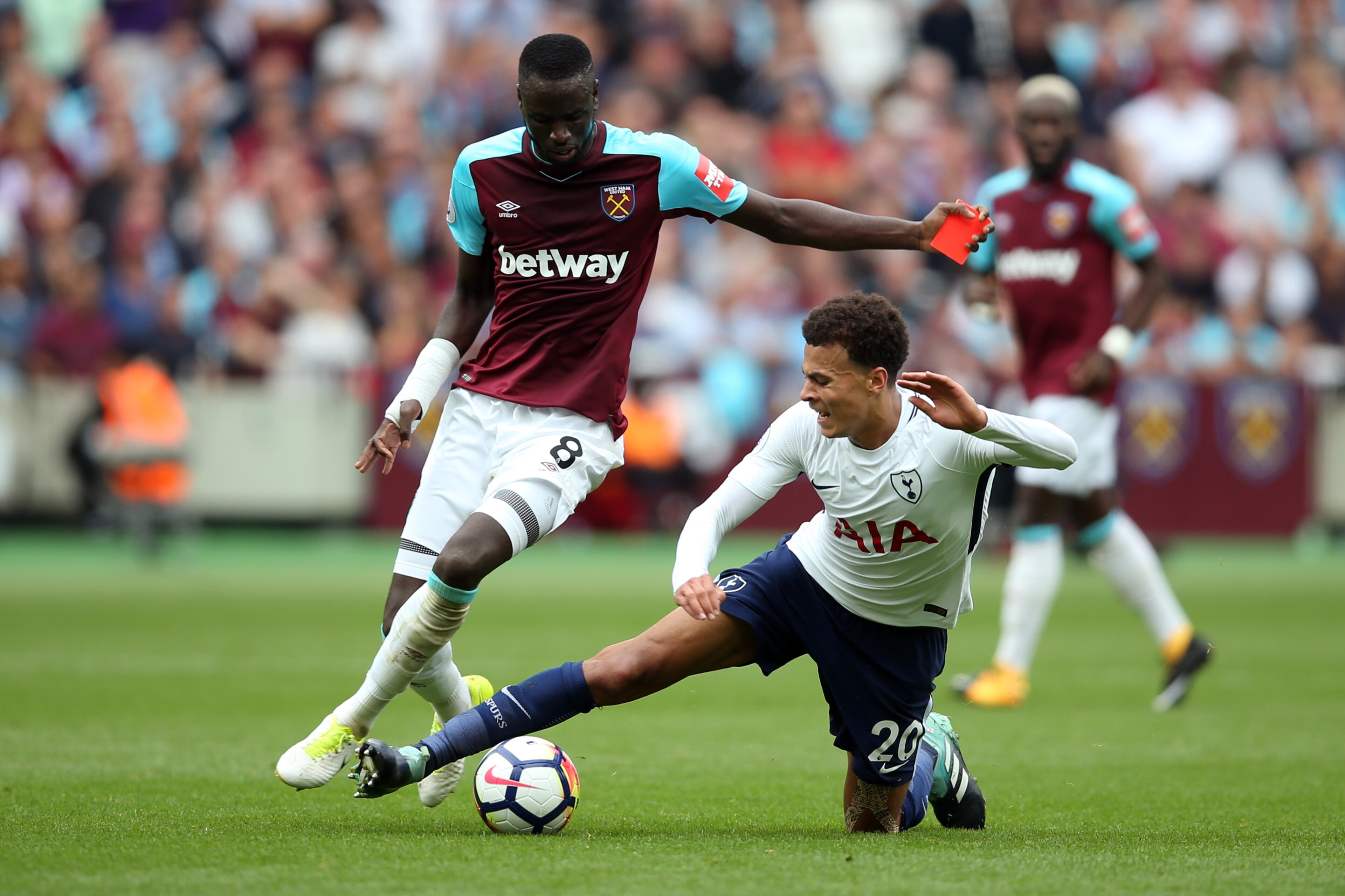 LONDON, ENGLAND - SEPTEMBER 23: Dele Alli of Tottenham Hotspur tackles Cheikhou Kouyate of West Ham United who is carrying a red card during the Premier League match between West Ham United and Tottenham Hotspur at London Stadium on September 23, 2017 in 