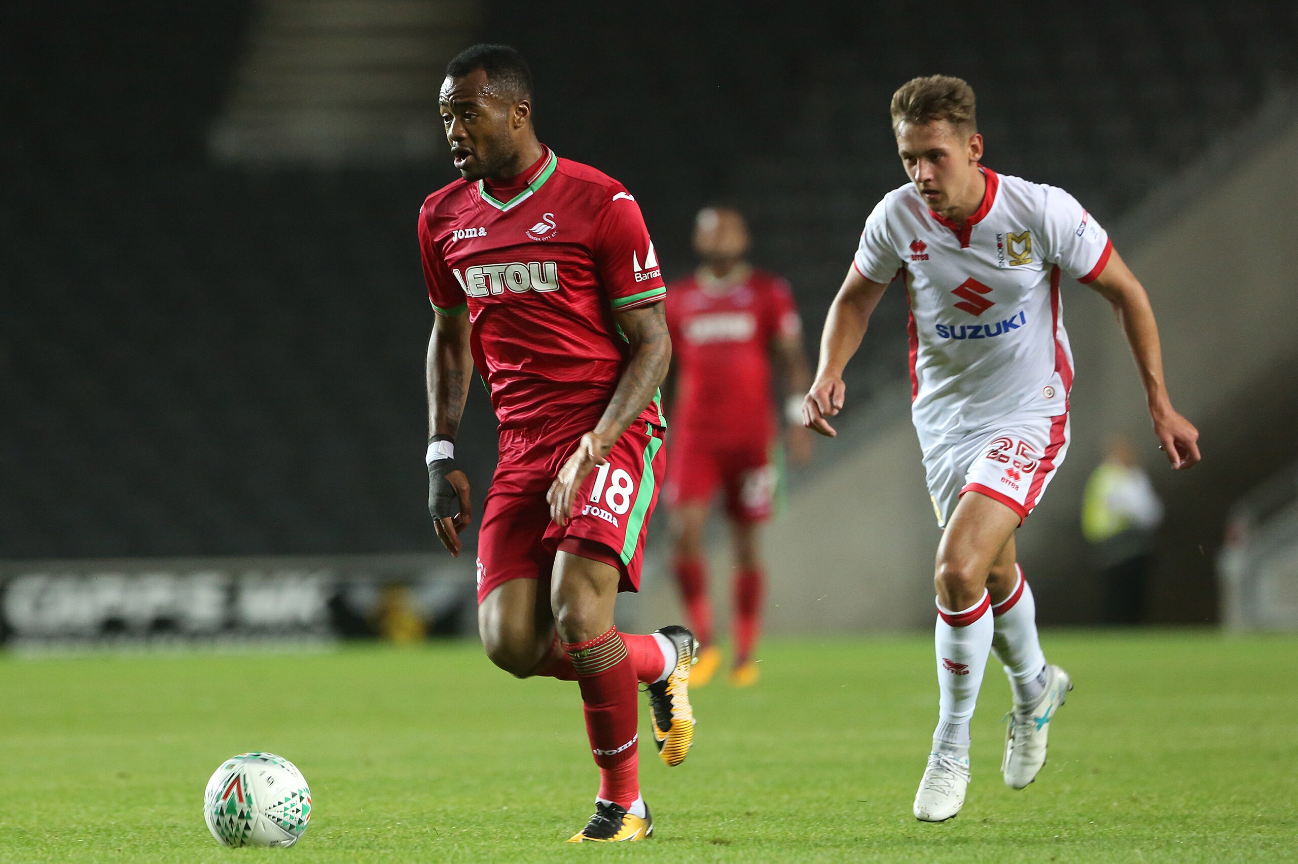 MILTON KEYNES, ENGLAND - AUGUST 22: Jordan Ayew of Swansea City is challenged by Callum Brittain of MK Dons during the Carabao Cup Second Round match between MK Dons and Swansea City at StadiumMK on August 22, 2017 in Milton Keynes, England. (Photo by Ath