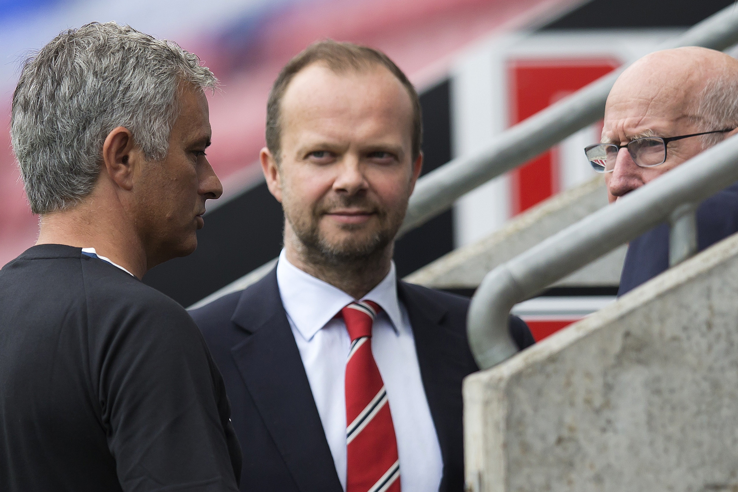 Manchester United's executive vice-chairman Ed Woodward (C) listens as Manchester United's Portuguese manager Jose Mourinho (L) talks with former Manchester United player Bobby Charlton following the pre-season friendly football match between Wigan Athlet