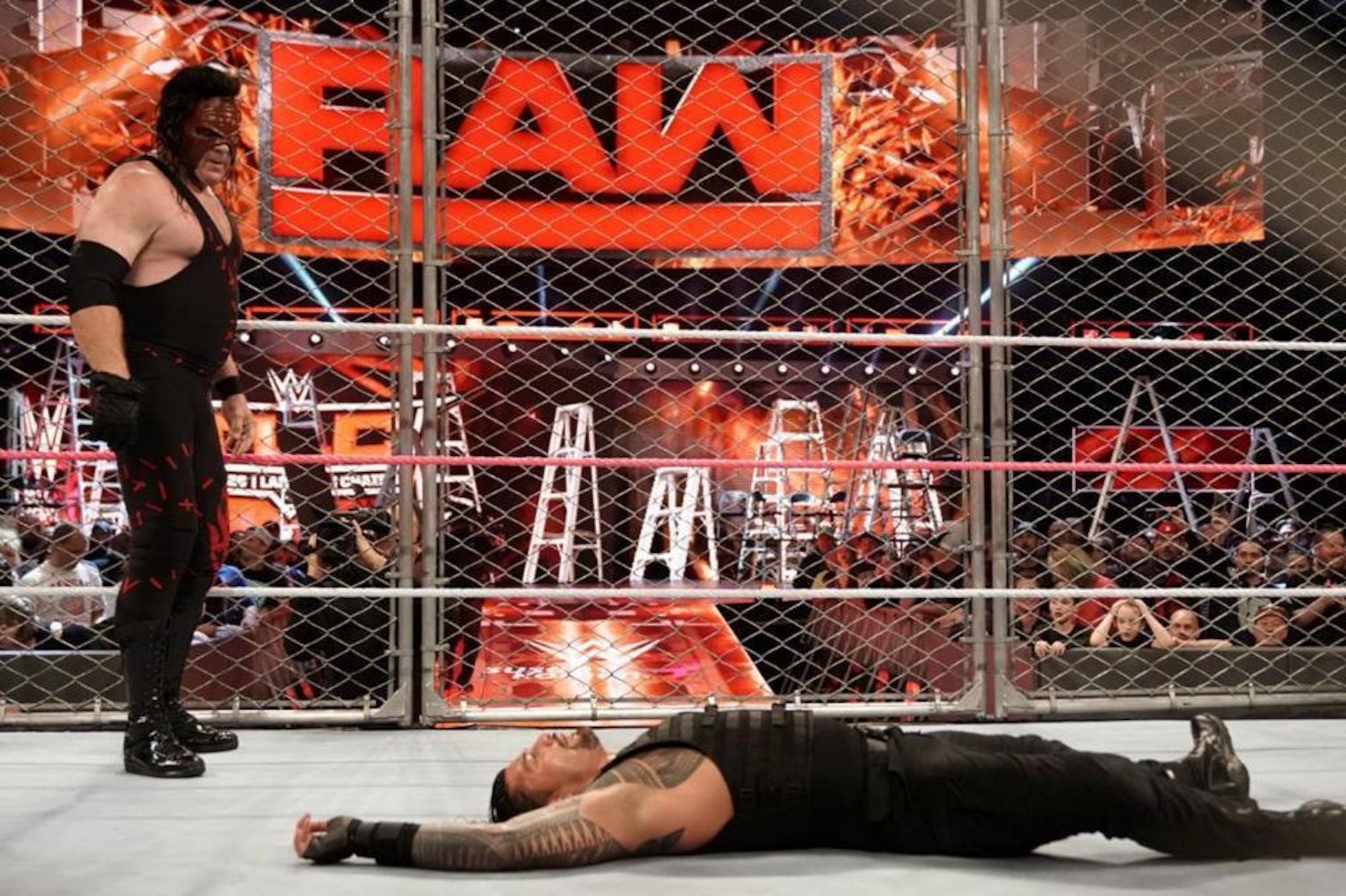 Kane eyes a fallen Roman Reigns.