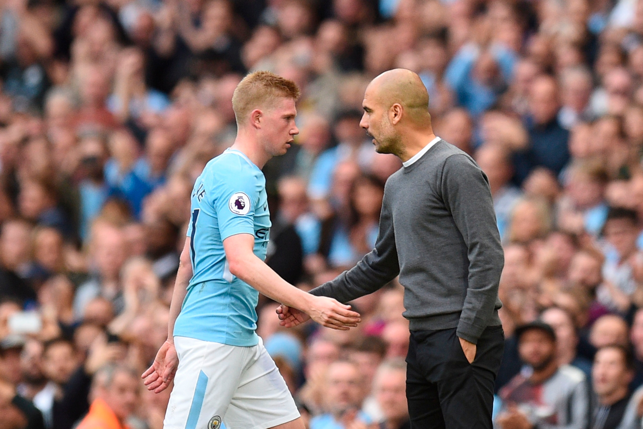 Manchester City's Belgian midfielder Kevin De Bruyne (L) walks by Manchester City's Spanish manager Pep Guardiola (R) as he is substituted during the English Premier League football match between Manchester City and Stoke City at the Etihad Stadium in Man