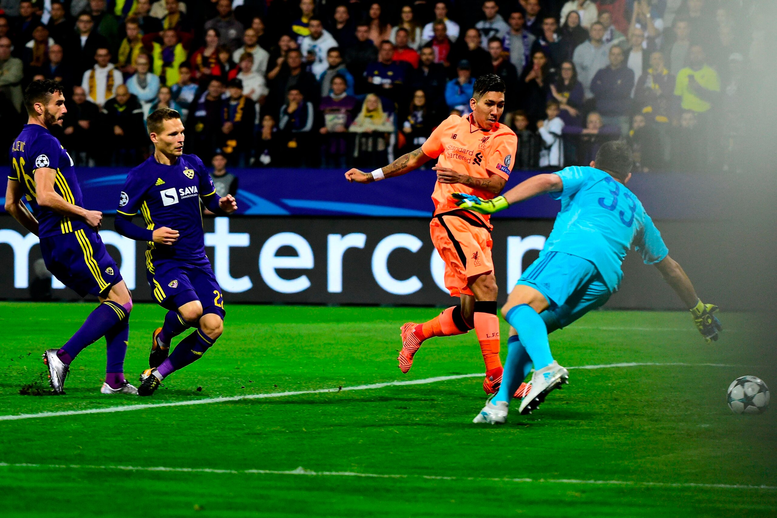 Liverpool's Brazilian forward Roberto Firmino (C) shoots and scores a goal past Maribor's Slovenian goalkeeper Jasmin Handanovic (R) during the UEFA Champions League group E football match between NK Maribor and Liverpool at the Ljudski vrt Stadium, in Ma
