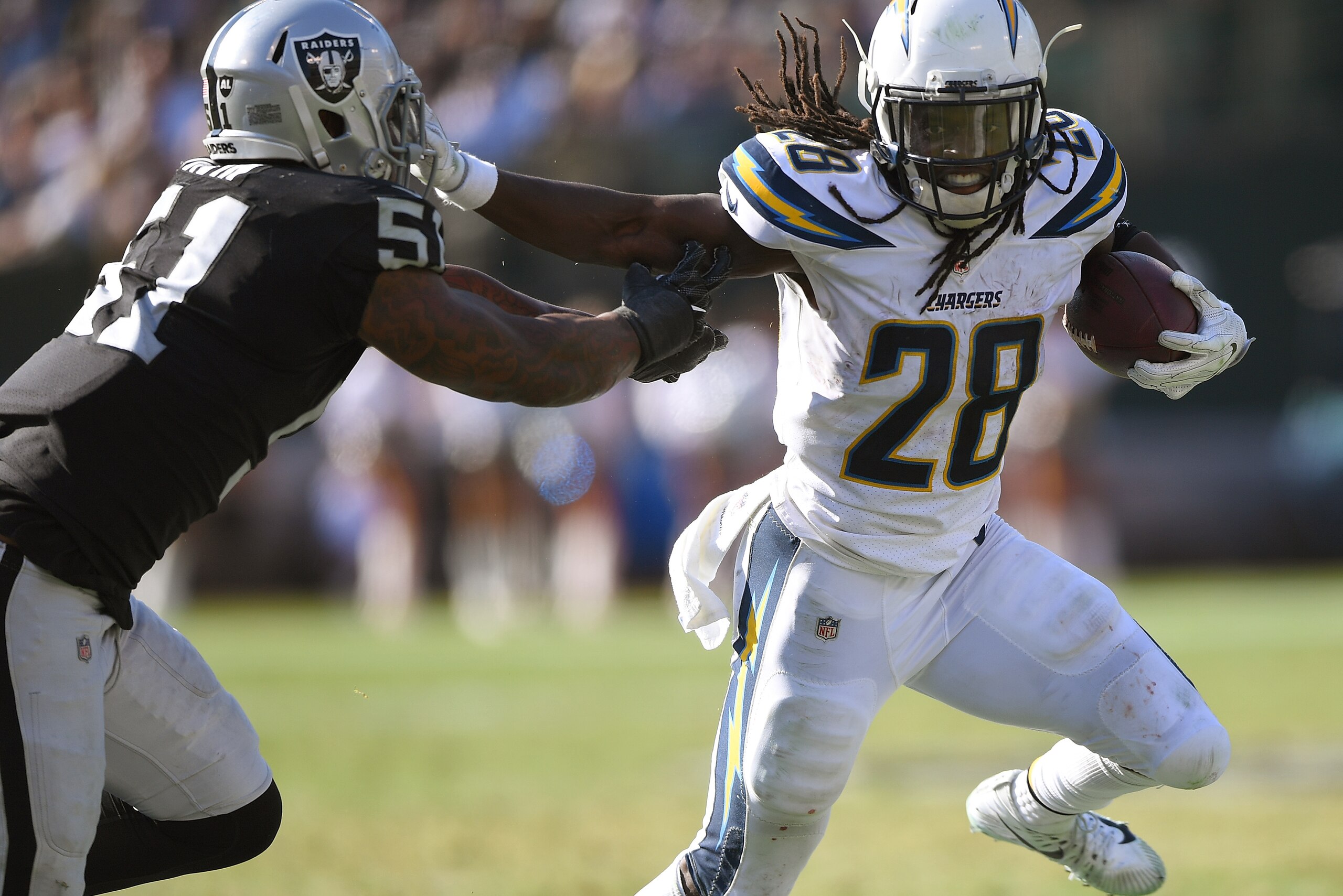 OAKLAND, CA - OCTOBER 15:  Melvin Gordon #28 of the Los Angeles Chargers fights off the tackle of Bruce Irvin #51 of the Oakland Raiders during an NFL football game at Oakland-Alameda County Coliseum on October 15, 2017 in Oakland, California.  (Photo by 