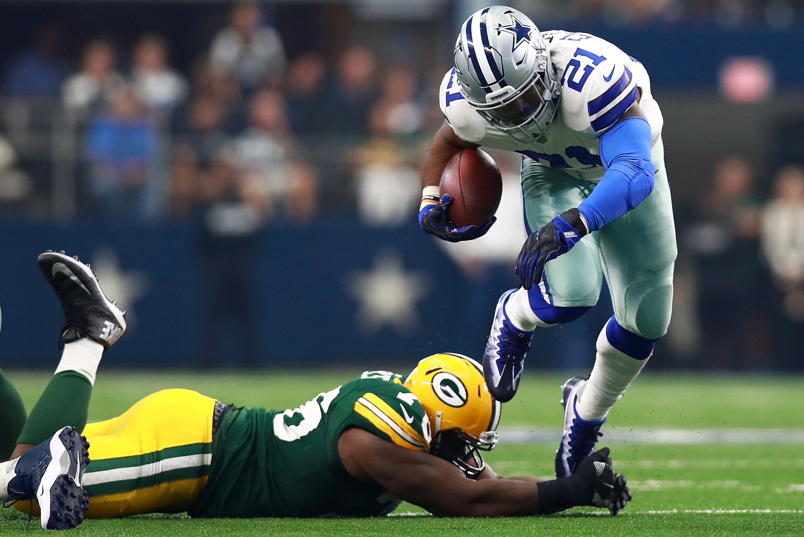 ARLINGTON, TX - OCTOBER 08:  Ezekiel Elliott #21 of the Dallas Cowboys carries the ball as Mike Daniels #76 of the Green Bay Packers tries to make the tackle in the first half of a football game at AT&T Stadium on October 8, 2017 in Arlington, Texas.  (Ph