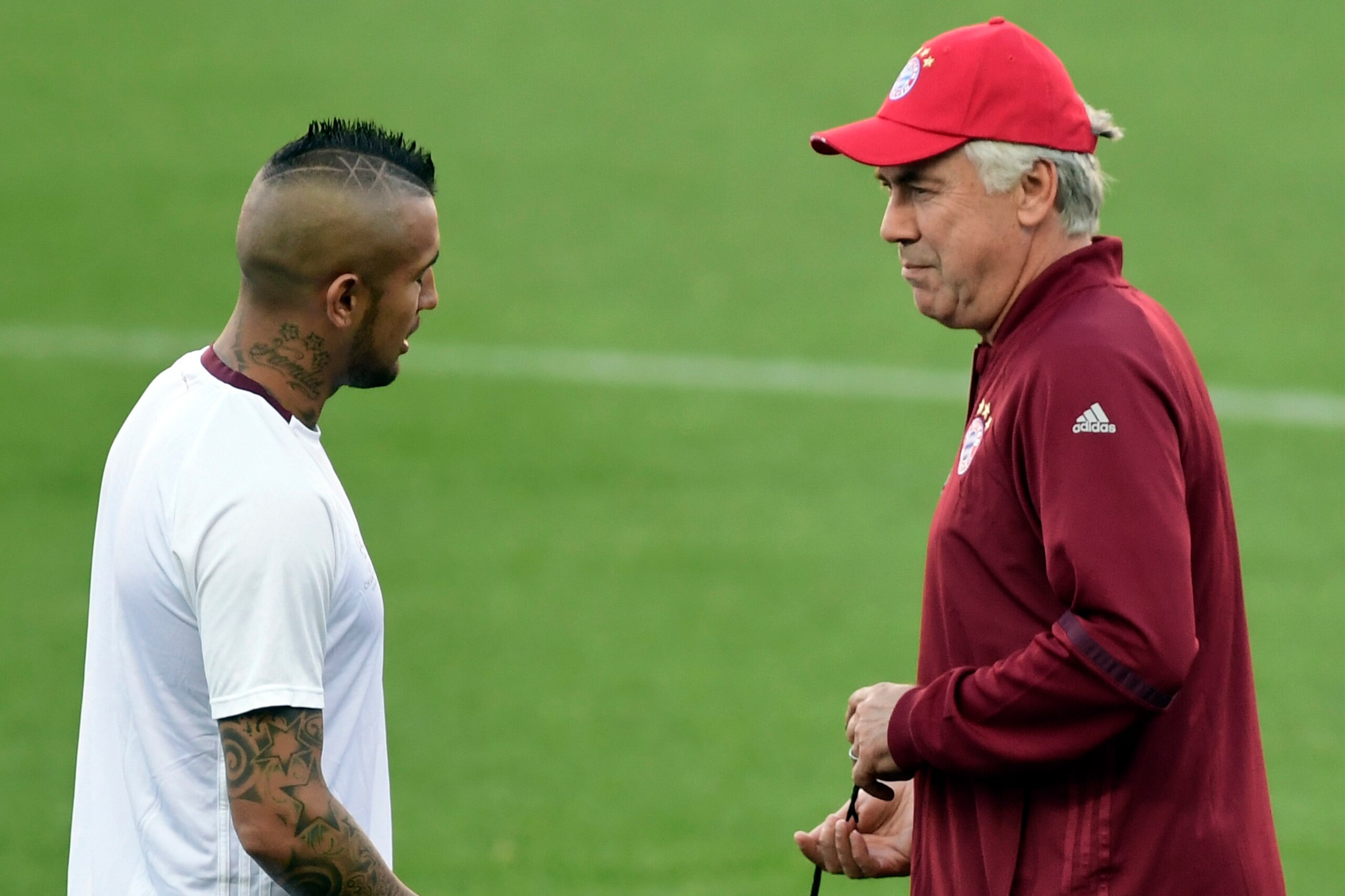 Bayern Munich's Italian head coach Carlo Ancelotti (R) speaks with Bayern Munich's Chilean midfielder Arturo Vidal during a training session at the Vicente Calderon stadium in Madrid on September 27, 2016 on the eve of their UEFA Champions league match ag