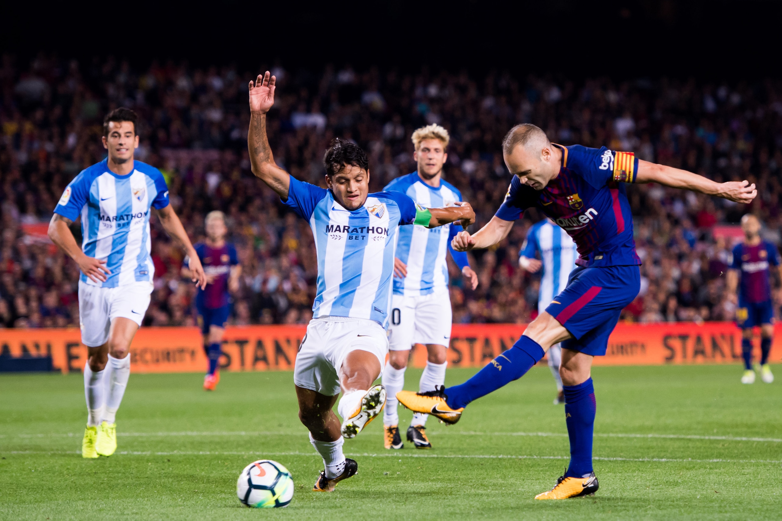 BARCELONA, SPAIN - OCTOBER 21: Andres Iniesta of FC Barcelona shoots the ball under pressure from Roberto Rosales of Malaga CF and scores his team's second goal during the La Liga match between Barcelona and Malaga at Camp Nou on October 21, 2017 in Barce
