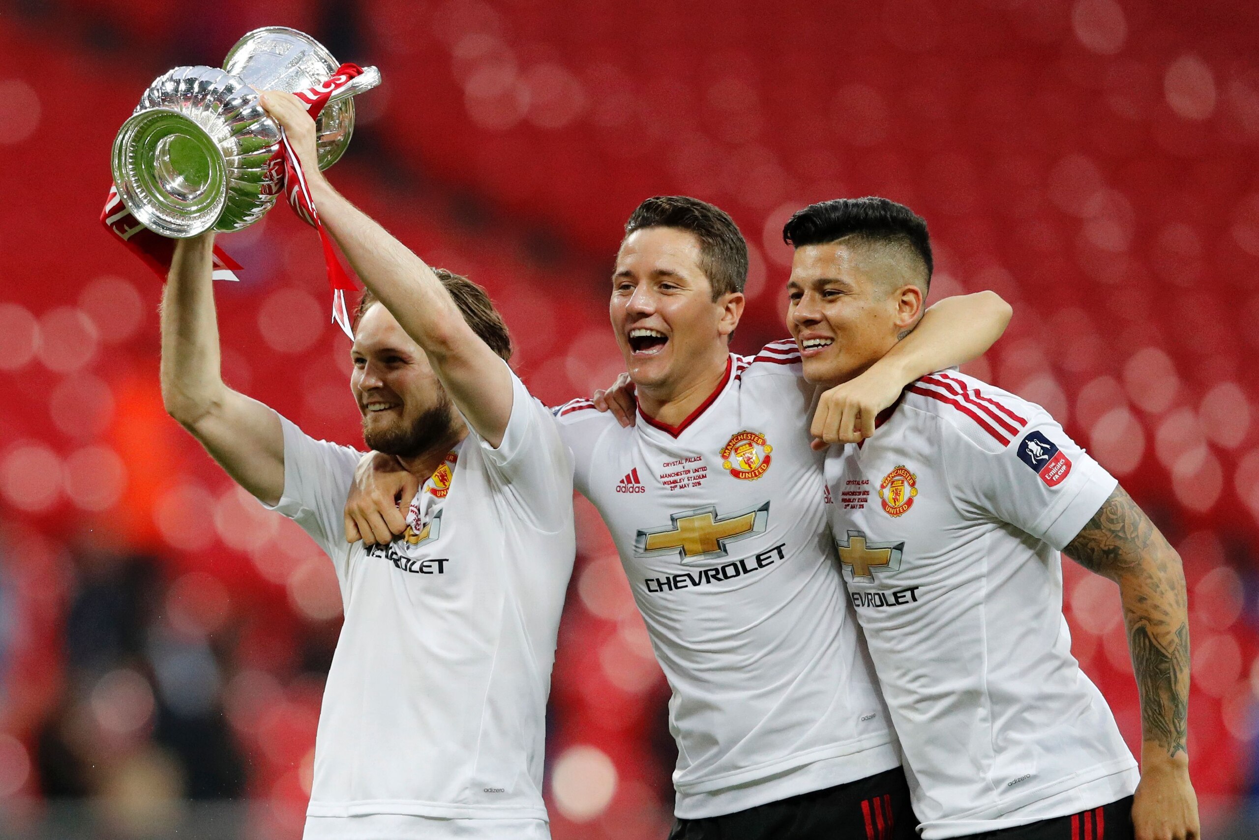 Manchester United's Dutch midfielder Daley Blind (L) holds up the trophy as he celebrates on the pitch with Manchester United's Spanish midfielder Ander Herrera (C) and Manchester United's Argentinian defender Marcos Rojo (R) after their victory after ext