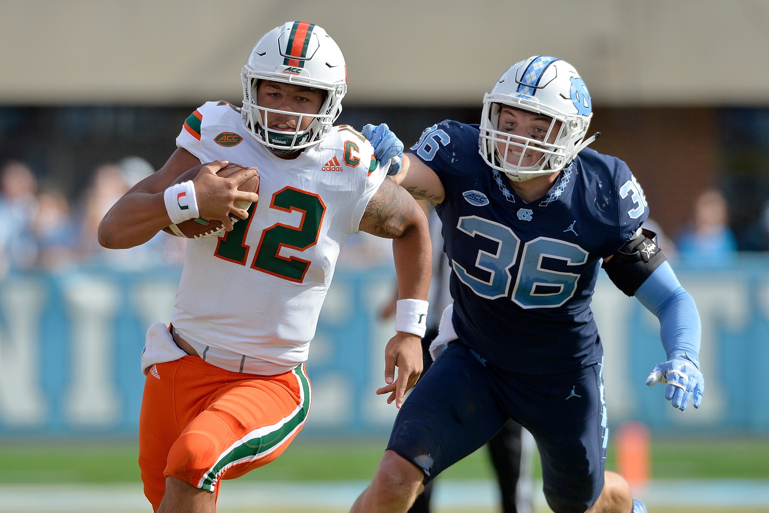 CHAPEL HILL, NC - OCTOBER 28:  Malik Rosier #12 of the Miami Hurricanes breaks away from Cole Holcomb #36 of the North Carolina Tar Heels during their game at Kenan Stadium on October 28, 2017 in Chapel Hill, North Carolina. Miami won 24-19.  (Photo by Gr
