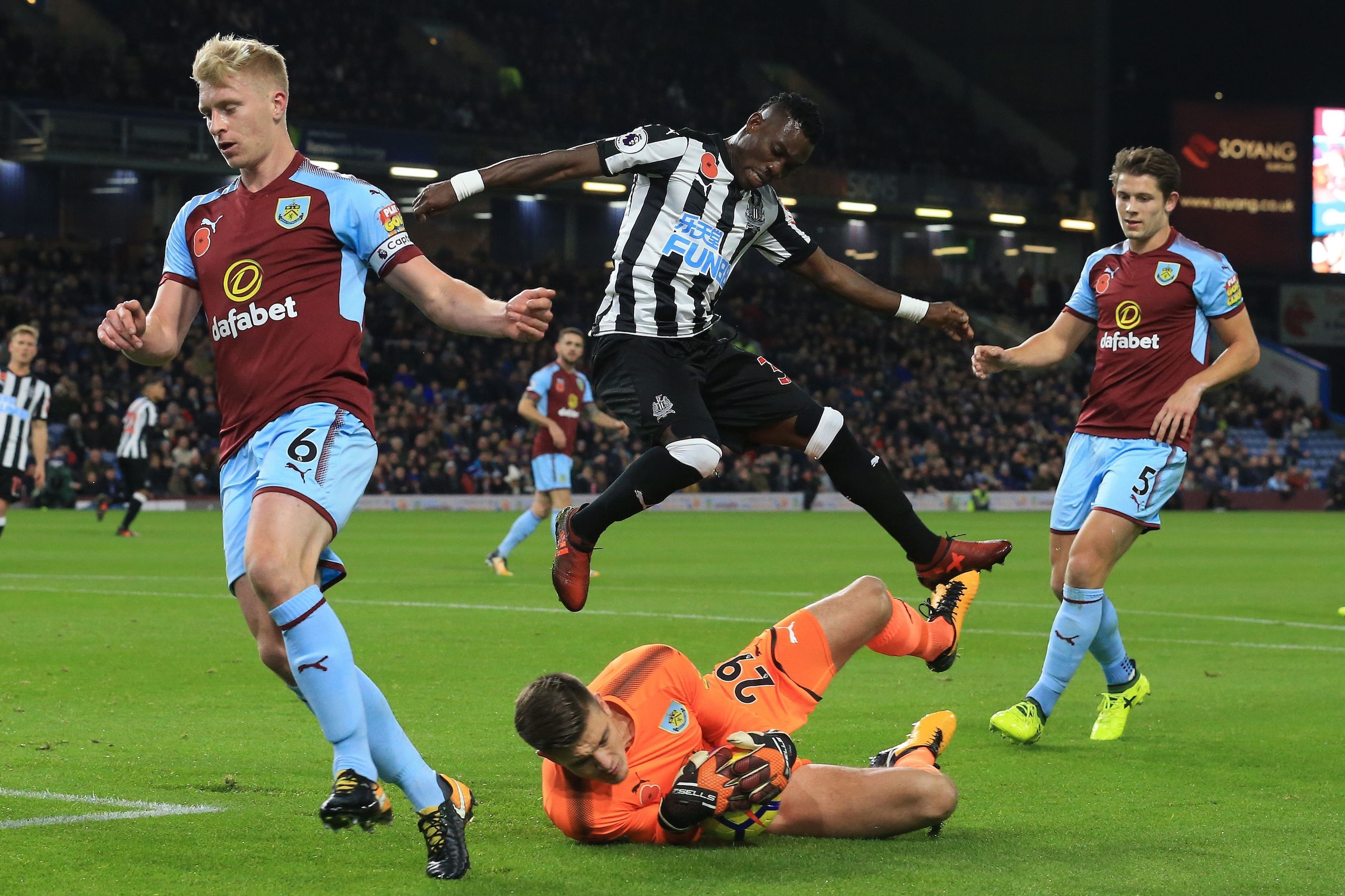 Newcastle United's Ghanaian midfielder Christian Atsu (C) jumps over Burnley's English goalkeeper Nick Pope during the English Premier League football match between Burnley and Newcastle United at Turf Moor in Burnley, north west England on October 30, 20
