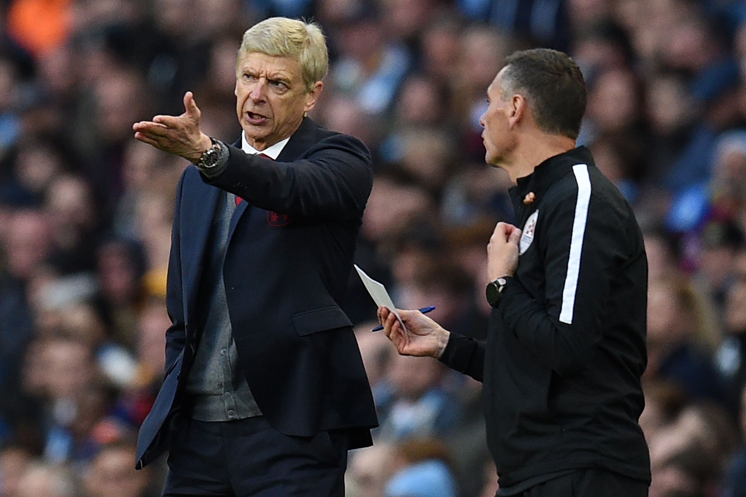 Arsenal's French manager Arsene Wenger (L) speaks to fourth official Andre Marriner after they concede their third goal during the English Premier League football match between Manchester City and Arsenal at the Etihad Stadium in Manchester, north west En