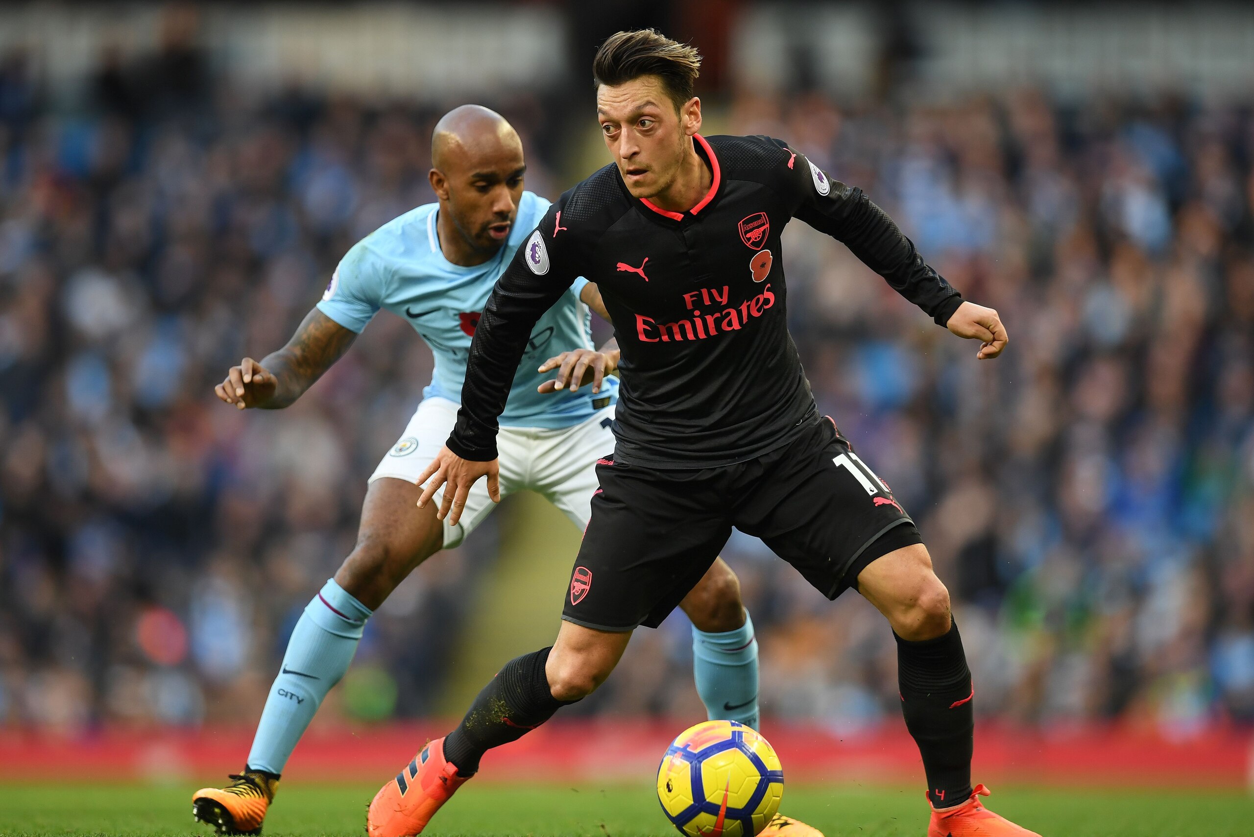 Manchester City's English midfielder Fabian Delph (L) vies with Arsenal's German midfielder Mesut Ozil during the English Premier League football match between Manchester City and Arsenal at the Etihad Stadium in Manchester, north west England, on Novembe