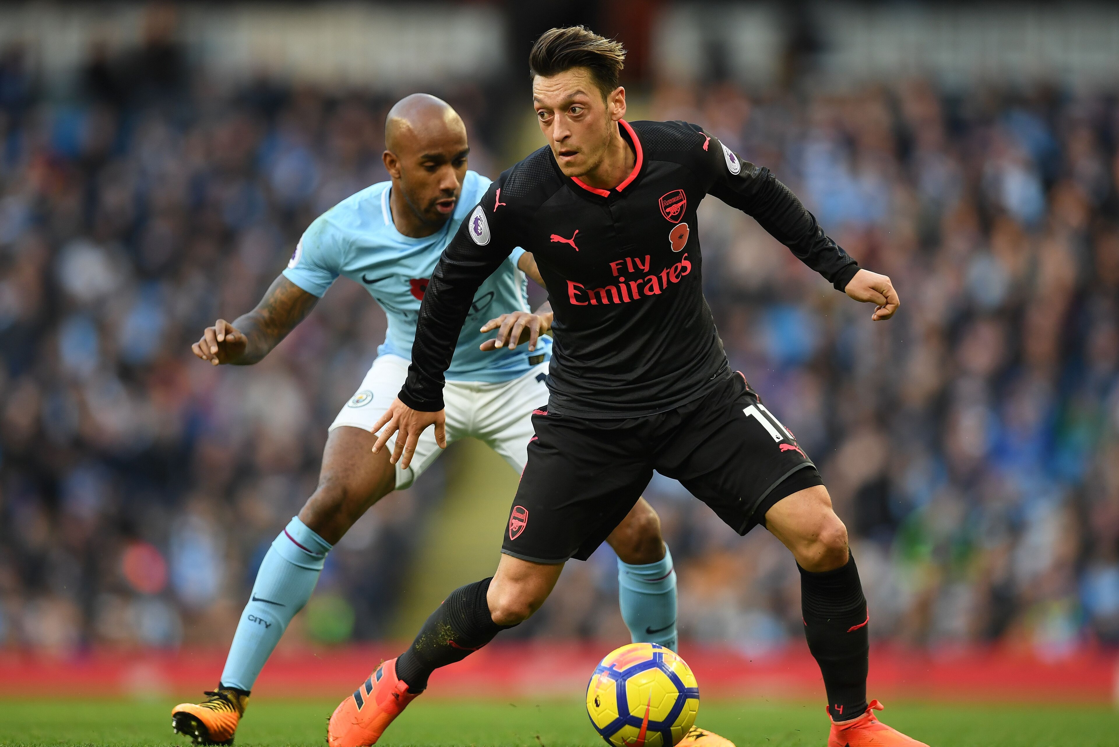 Manchester City's English midfielder Fabian Delph (L) vies with Arsenal's German midfielder Mesut Ozil during the English Premier League football match between Manchester City and Arsenal at the Etihad Stadium in Manchester, north west England, on Novembe