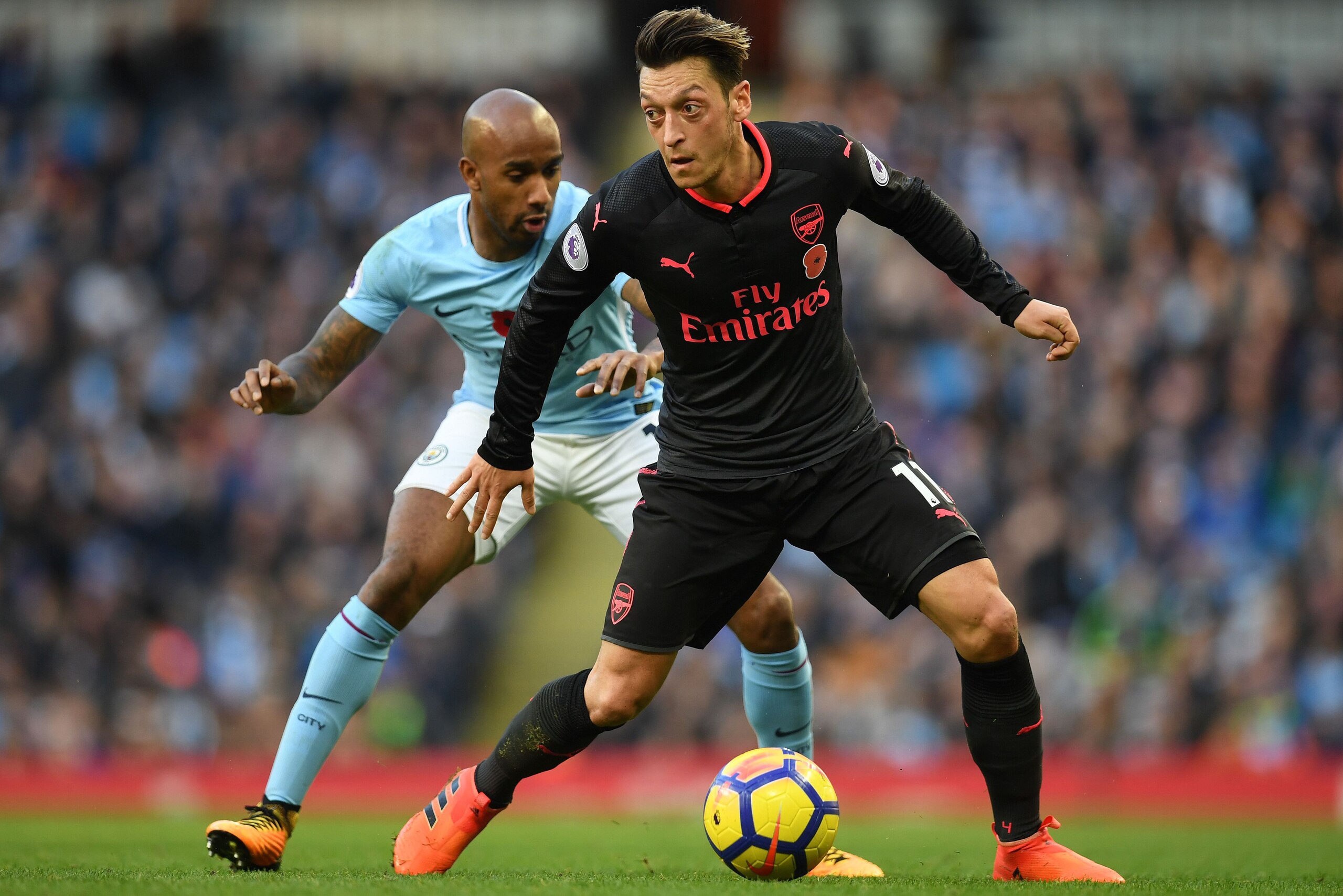 Manchester City's English midfielder Fabian Delph (L) vies with Arsenal's German midfielder Mesut Ozil during the English Premier League football match between Manchester City and Arsenal at the Etihad Stadium in Manchester, north west England, on Novembe
