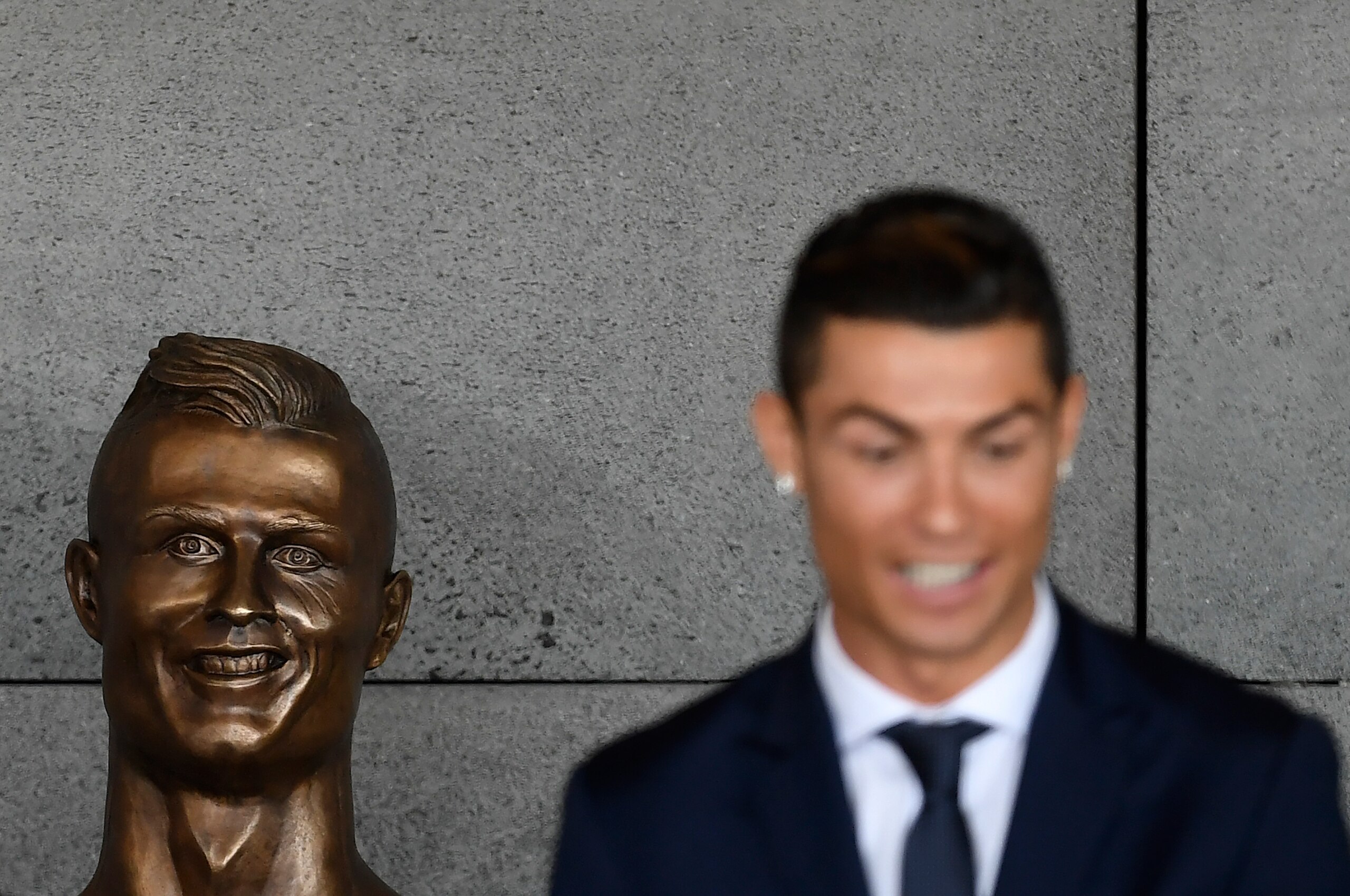 Portuguese footballer Cristiano Ronaldo stands beside a bust presented during a ceremony to rename Madeira's airport in Funchal as 'Cristiano Ronaldo', on Madeira island, on March 29, 2017. 
Airport of Madeira, the birthplace of Portuguese footballer Cris
