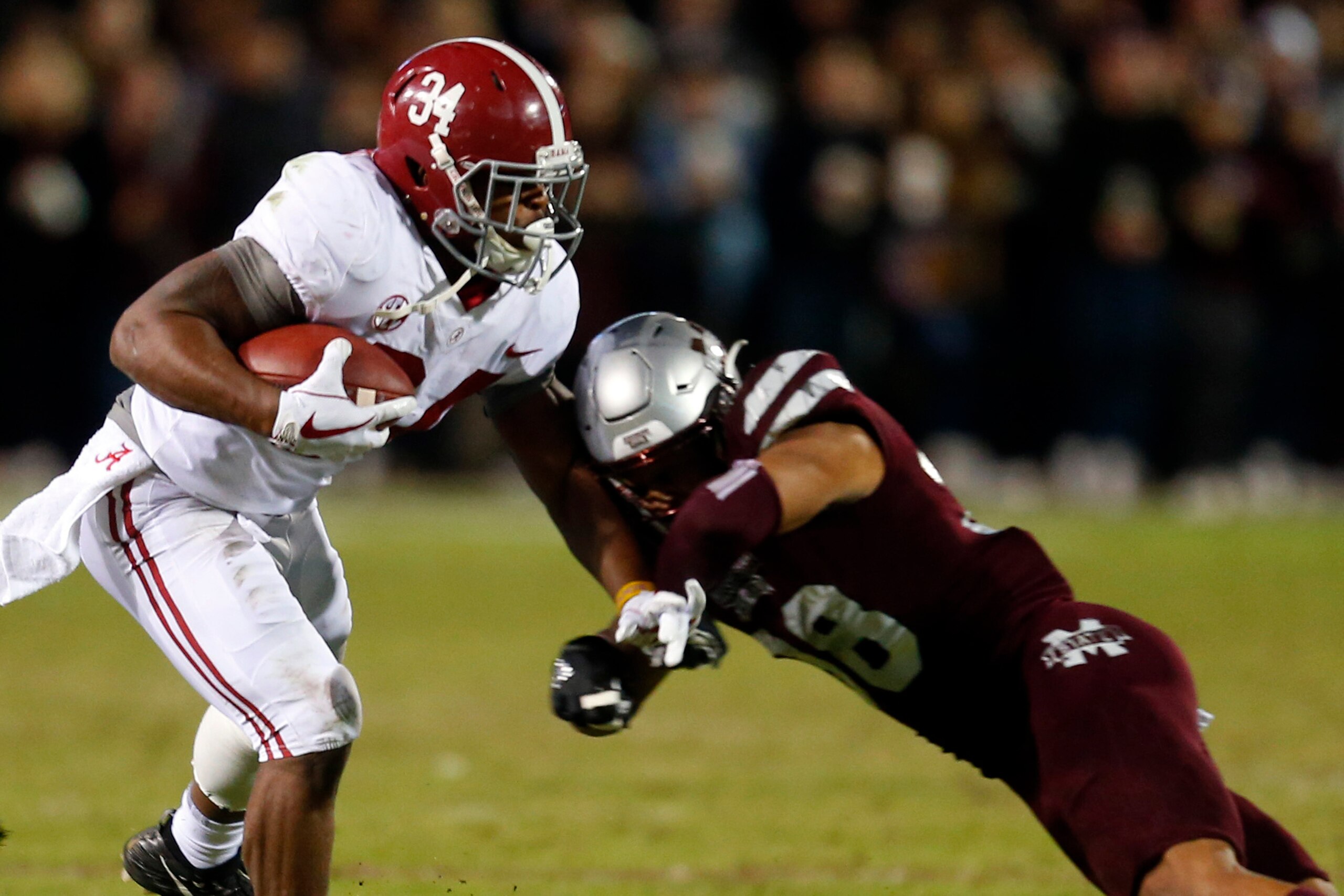 STARKVILLE, MS - NOVEMBER 11:  Damien Harris #34 of the Alabama Crimson Tide carries the ball as he is tackled by Johnathan Abram #38 of the Mississippi State Bulldogs during the second half of an NCAA football game at Davis Wade Stadium on November 11, 2