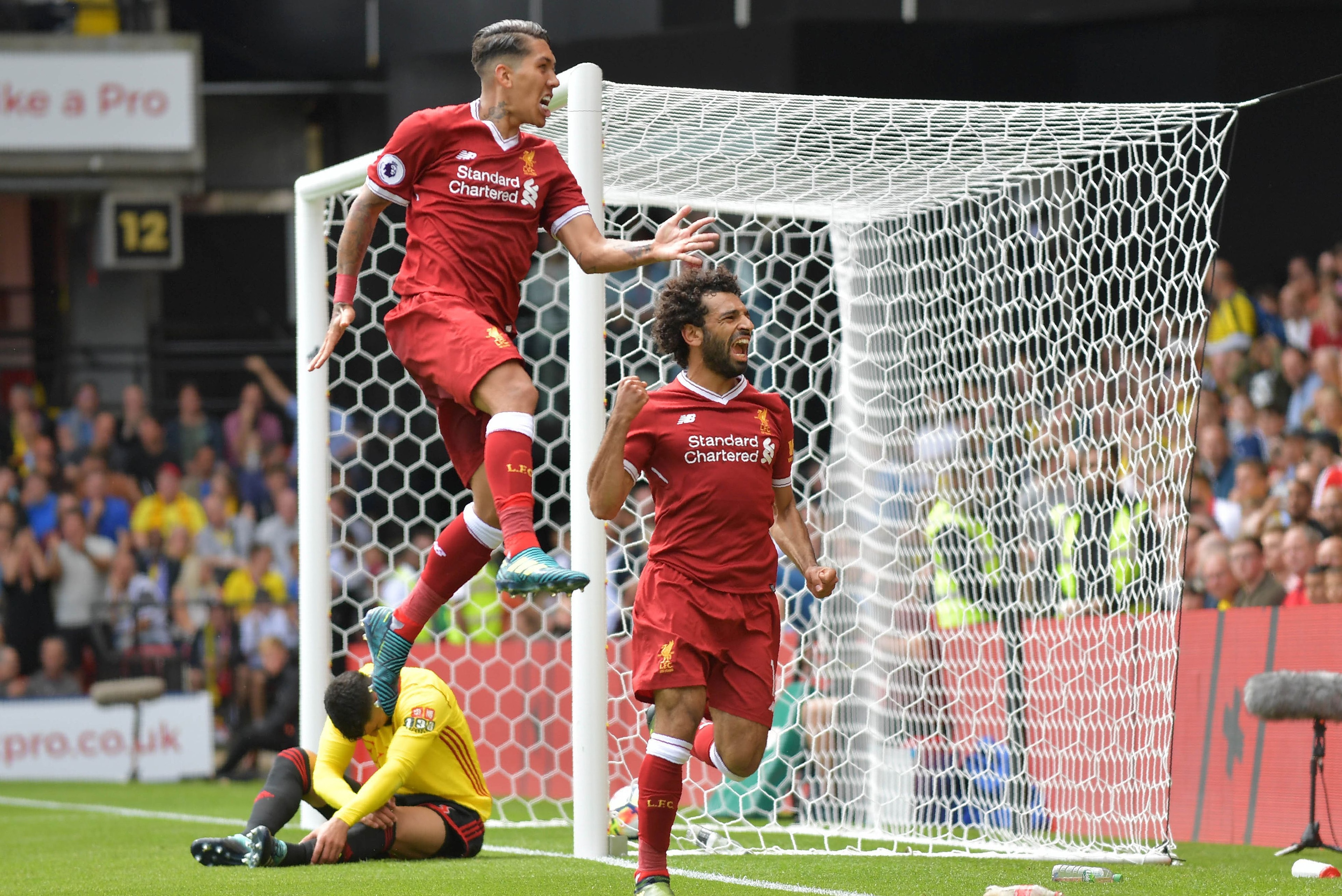 Liverpool's Egyptian midfielder Mohamed Salah (R) celebrates scoring his team's third goal with Liverpool's Brazilian midfielder Roberto Firmino during the English Premier League football match between Watford and Liverpool at Vicarage Road Stadium in Wat