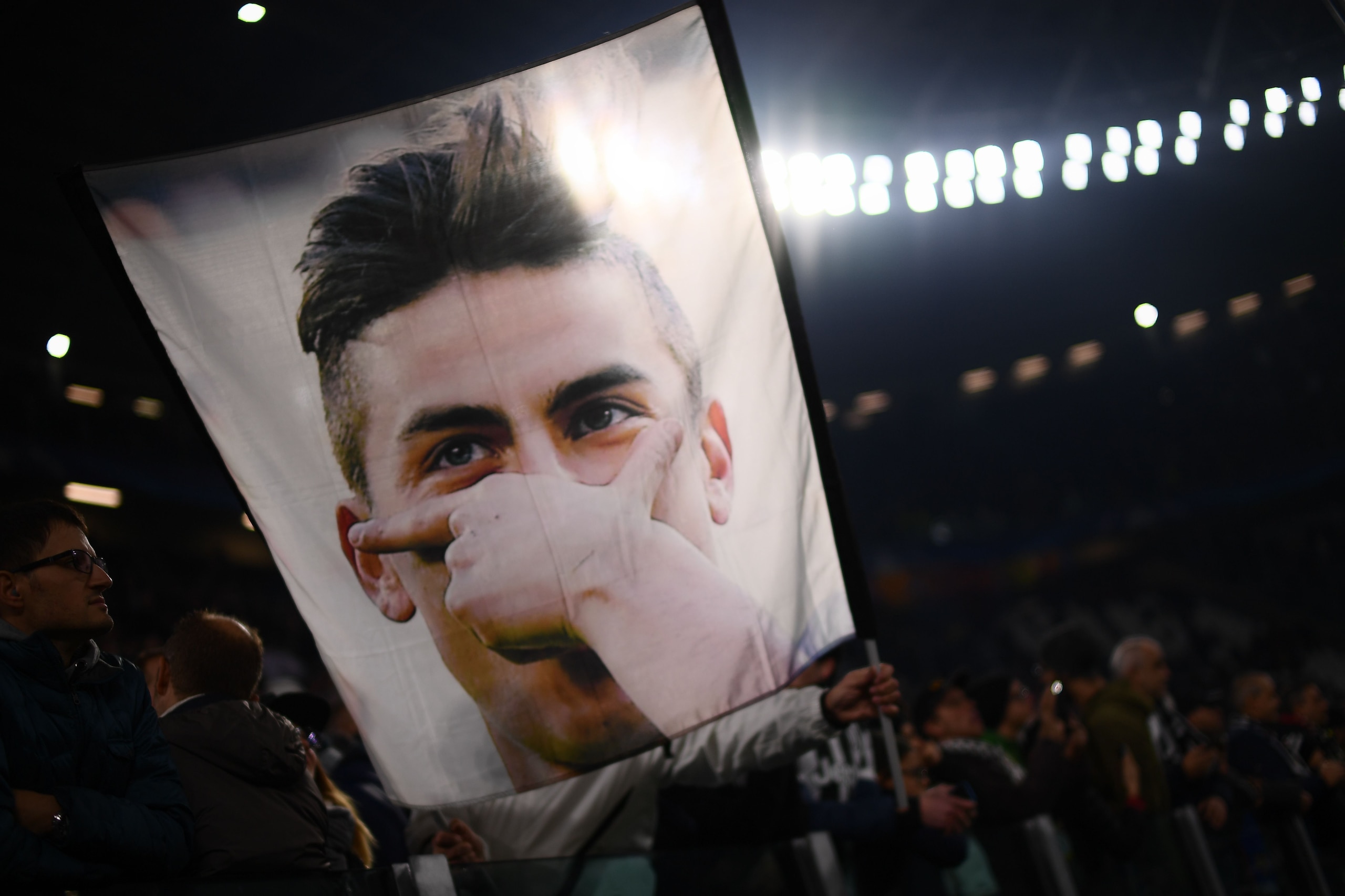 Juventus' fans wave a flag showing a portrait of Juventus' forward from Argentina Paulo Dybala before the UEFA Champions League Group F football match Napoli vs Shakhtar Donetsk on November 21, 2017 at the San Paolo stadium in Naples.  / AFP PHOTO / Marco