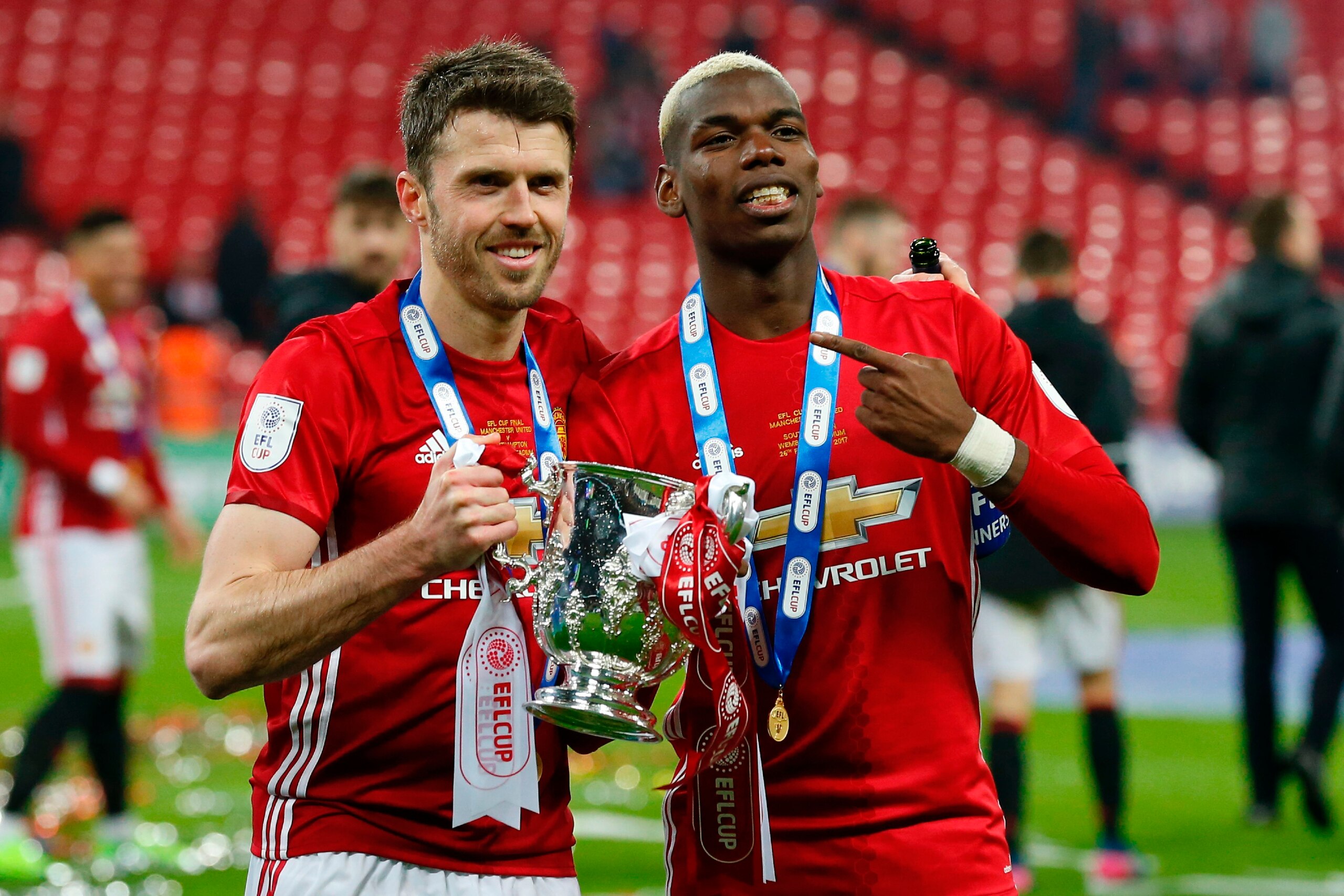 Manchester United's French midfielder Paul Pogba (R) and Manchester United's English midfielder Michael Carrick (L) celebrate with the trophy on the pitch after their victory in the English League Cup final football match between Manchester United and Sou