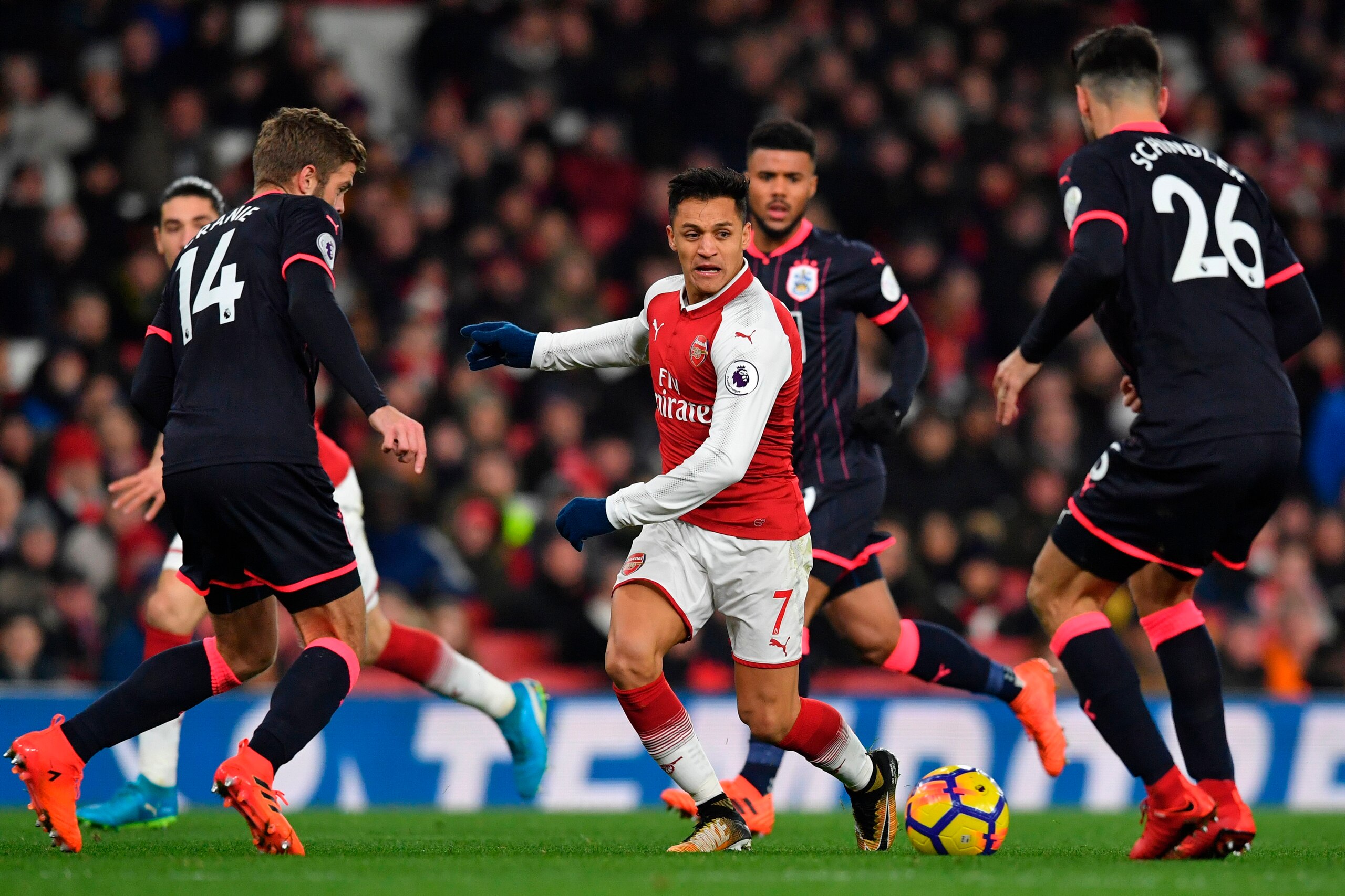 Arsenal's Chilean striker Alexis Sanchez (C) takes on Huddersfield Town's English defender Martin Cranie (L) and Huddersfield Town's German defender Christopher Schindler (R) during the English Premier League football match between Arsenal and Huddersfiel