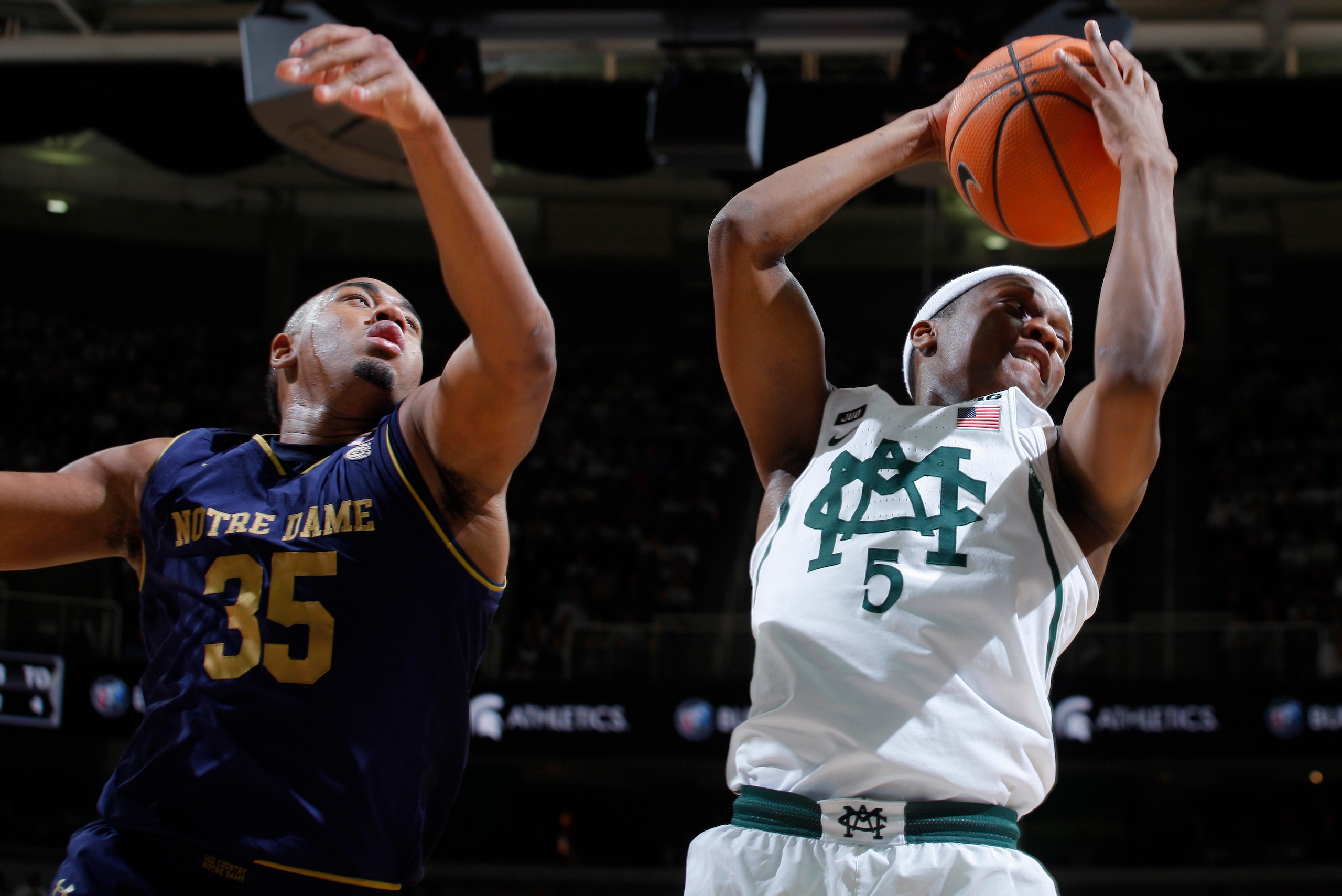 Cassius Winston takes a rebound away from Bonzie Colson.