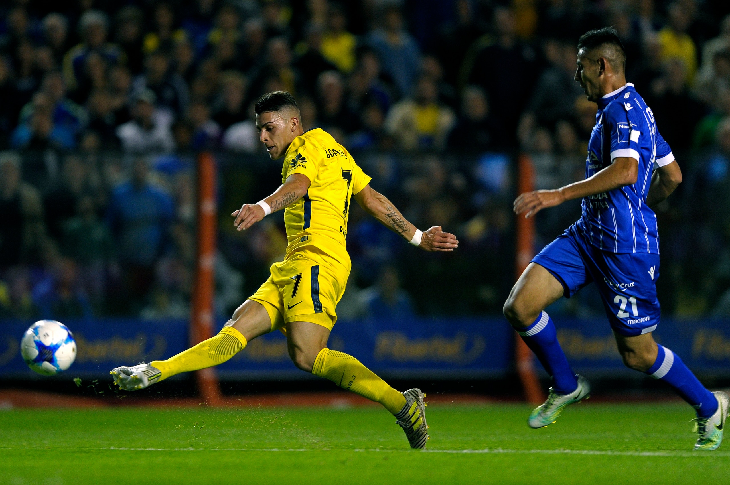 Boca Juniors' forward Cristian Pavon (L) kicks to score the team's third goal against Godoy Cruz during their Argentina First Division Superliga football match at La Bombonera  stadium, in Buenos Aires, on September 17, 2017. / AFP PHOTO / ALEJANDRO PAGNI