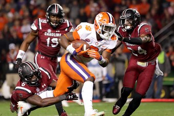 COLUMBIA, SC - NOVEMBER 25:  Travis Etienne #9 of the Clemson Tigers runs for a touchdown as teammates T.J. Brunson #6 and D.J. Smith #24 of the South Carolina Gamecocks try to stop him during their game at Williams-Brice Stadium on November 25, 2017 in C