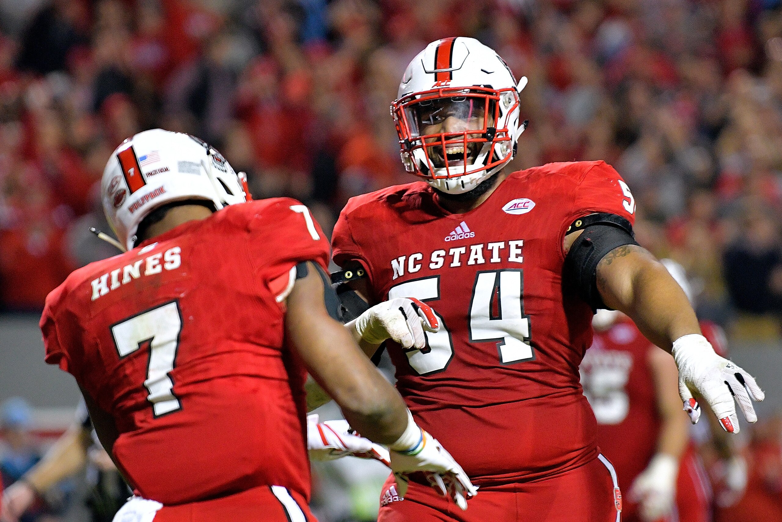 RALEIGH, NC - NOVEMBER 25:  Will Richardson #54 of the North Carolina State Wolfpack celebrates with Nyheim Hines #7 of the North Carolina State Wolfpack after Hines' touchdown against the North Carolina Tar Heels during their game at Carter Finley Stadiu