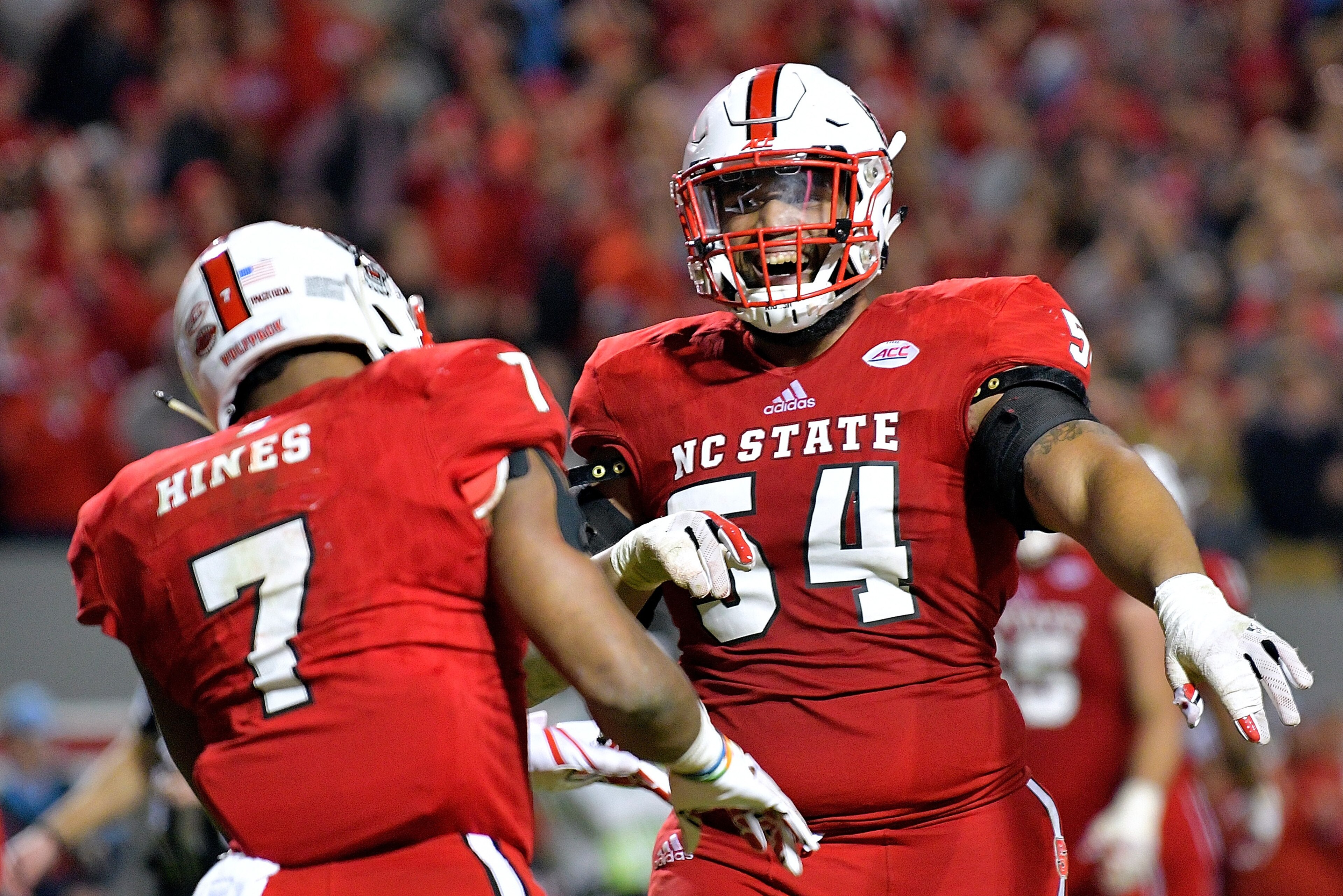 RALEIGH, NC - NOVEMBER 25:  Will Richardson #54 of the North Carolina State Wolfpack celebrates with Nyheim Hines #7 of the North Carolina State Wolfpack after Hines' touchdown against the North Carolina Tar Heels during their game at Carter Finley Stadiu