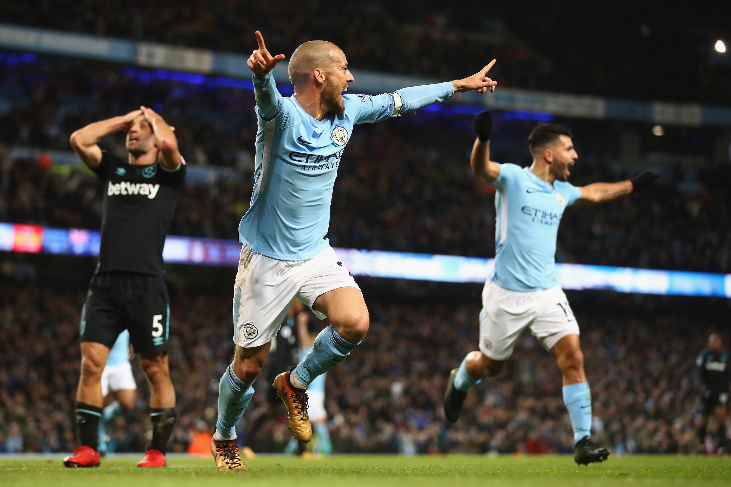 MANCHESTER, ENGLAND - DECEMBER 03:  David Silva of Manchester City celebrates scoring his sides second goal with team mate Sergio Aguero while Pablo Zabaleta of West Ham United looks dejected during the Premier League match between Manchester City and Wes