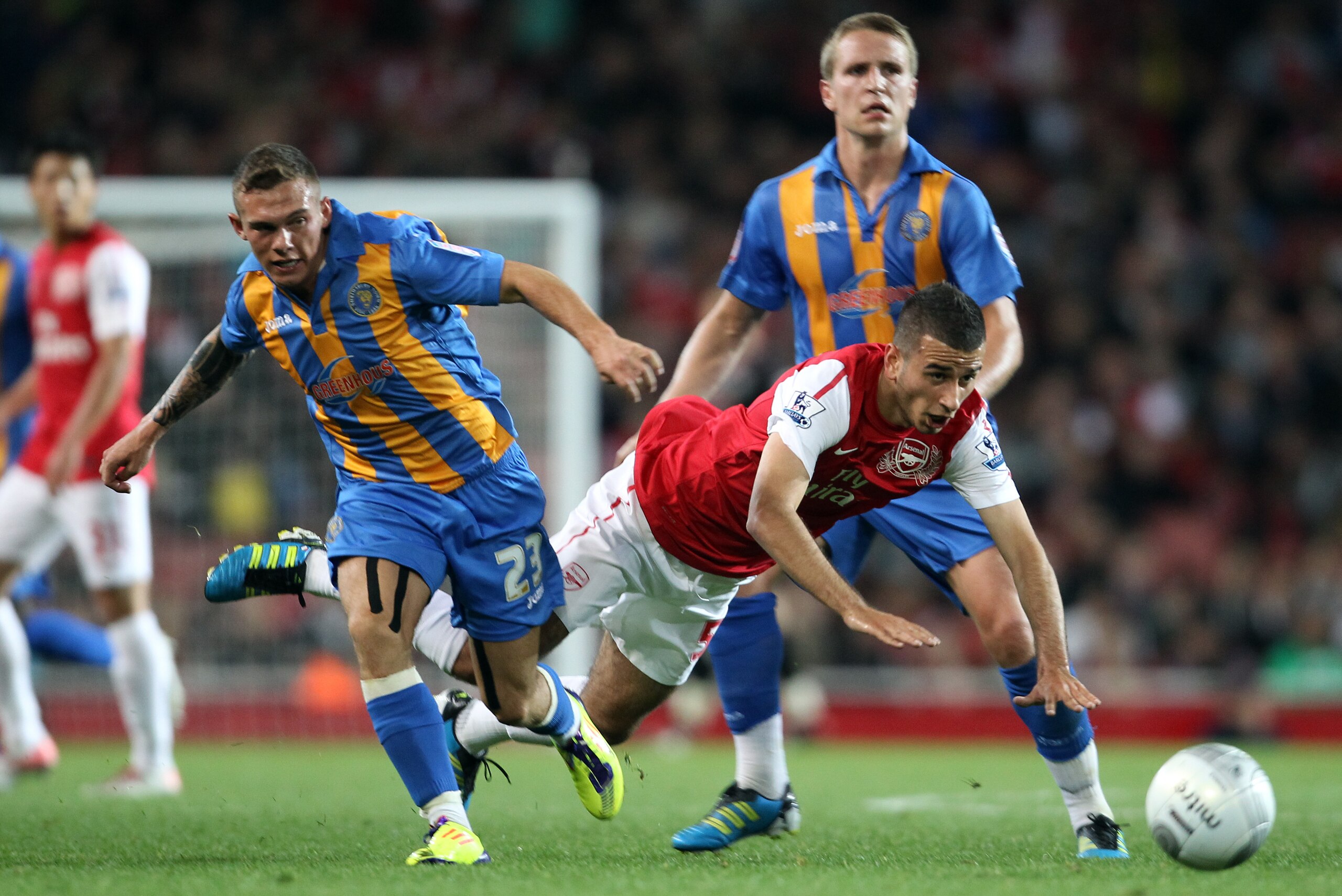 Shrewsbury Town's Jon Taylor (L) tackles Arsenal's Oguzhan Ozyakup (C) during the Carling Cup third round football match at the Emirates Stadium in London on September 20, 2011. Arsenal won 3-1.    AFP PHOTO/ ADRIAN DENNIS

RESTRICTED TO EDITORIAL USE. No