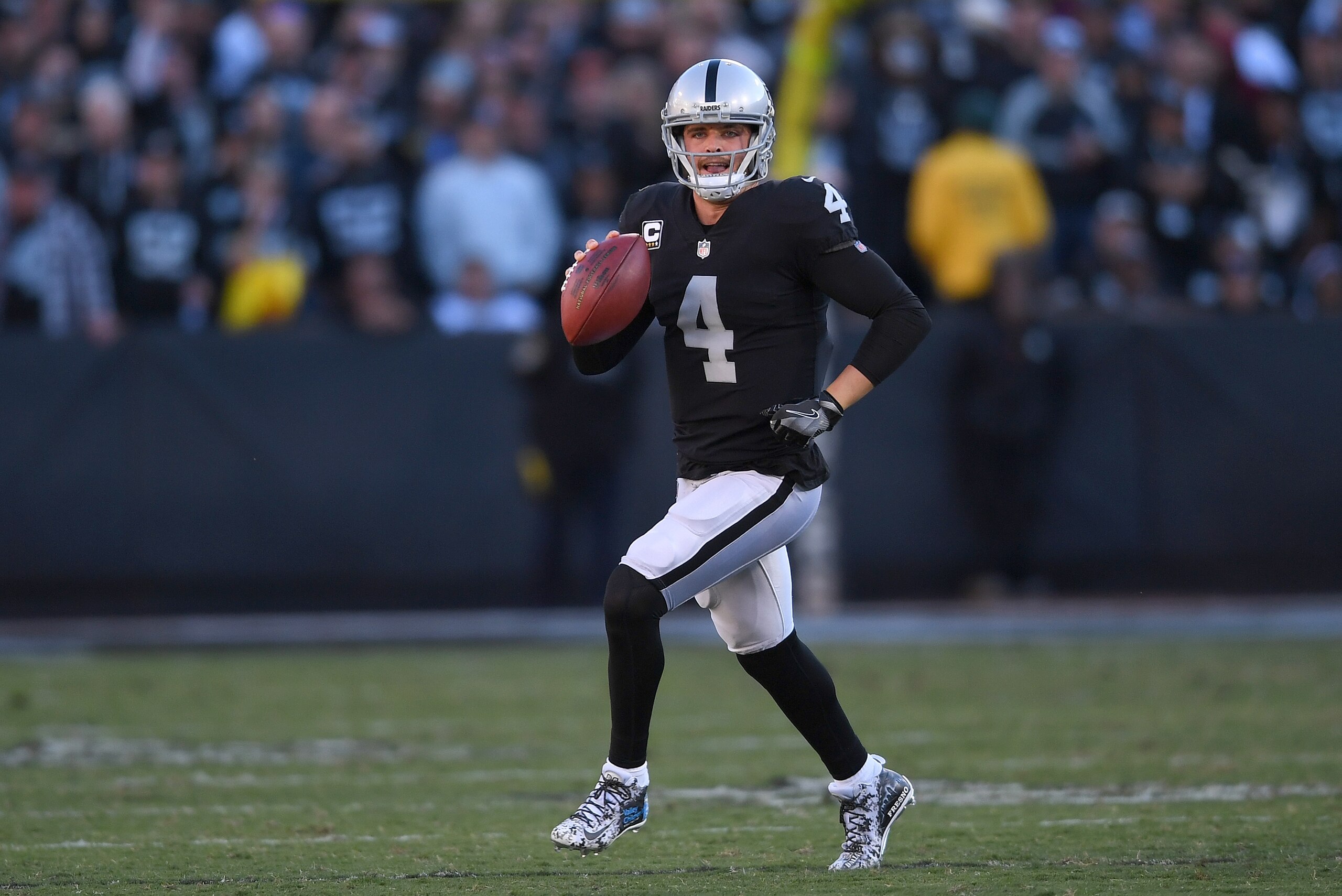 OAKLAND, CA - DECEMBER 03:  Derek Carr #4 of the Oakland Raiders looks to throw a pass while scrambling with the ball against the New York Giants during their NFL football game at Oakland-Alameda County Coliseum on December 3, 2017 in Oakland, California.