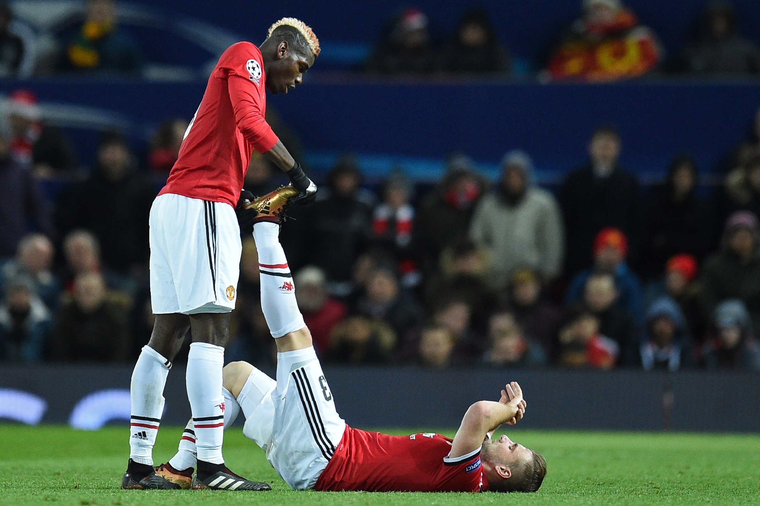 Manchester United's French midfielder Paul Pogba (L) assists Manchester United's English defender Luke Shaw, stricken by cramp during the UEFA Champions League Group A football match between Manchester United and CSKA Moscow at Old Trafford in Manchester,
