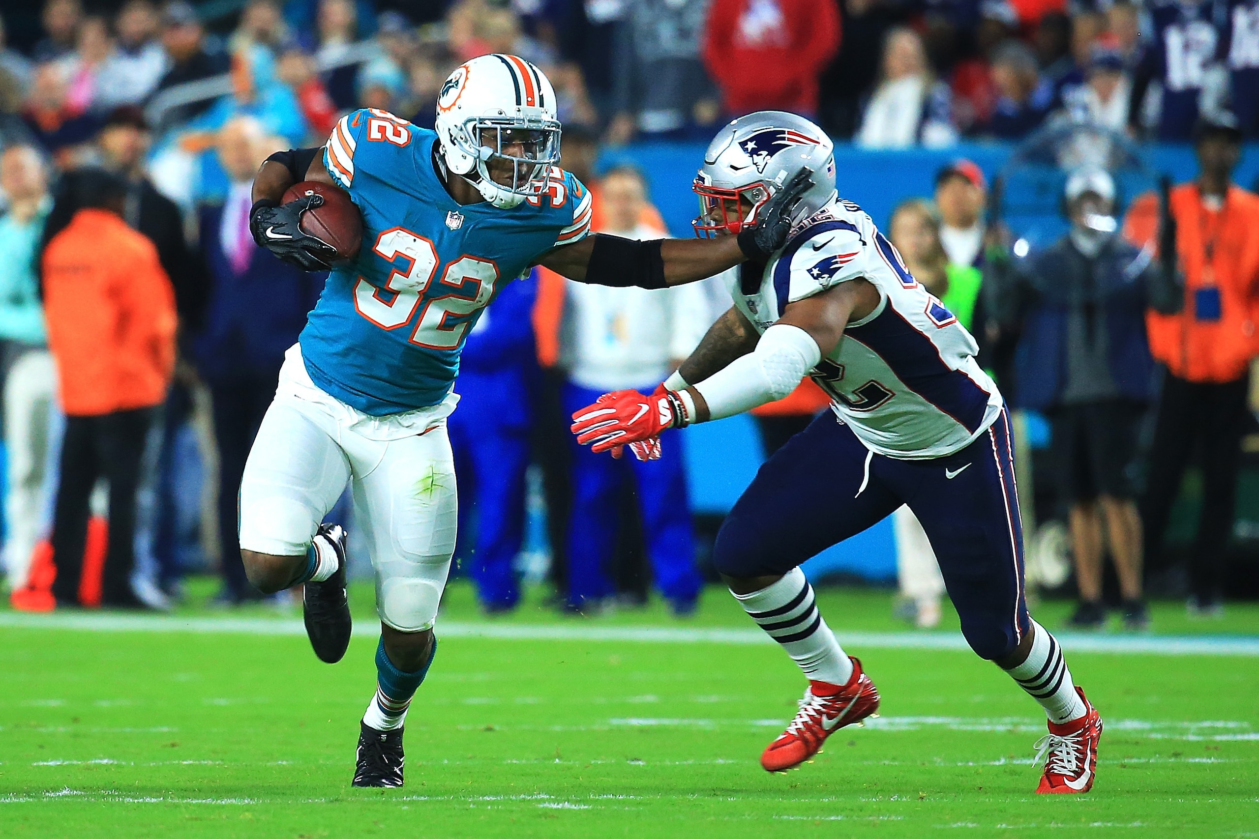 MIAMI GARDENS, FL - DECEMBER 11: Kenyan Drake #32 of the Miami Dolphins tries to avoid the tackle by Elandon Roberts #52 of the New England Patriots during the first quarter at Hard Rock Stadium on December 11, 2017 in Miami Gardens, Florida.  (Photo by C
