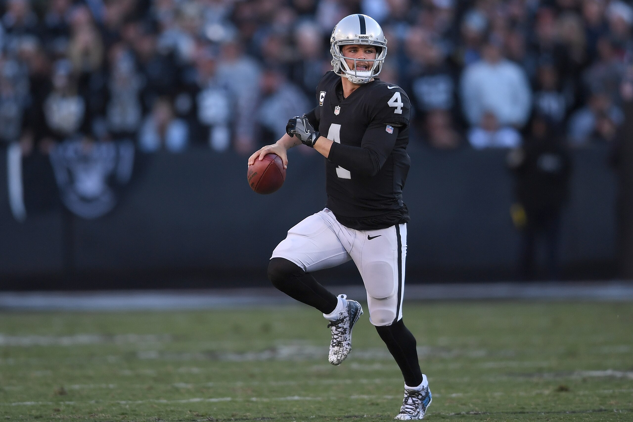 OAKLAND, CA - DECEMBER 03:  Derek Carr #4 of the Oakland Raiders looks to throw a pass while scrambling with the ball against the New York Giants during their NFL football game at Oakland-Alameda County Coliseum on December 3, 2017 in Oakland, California.