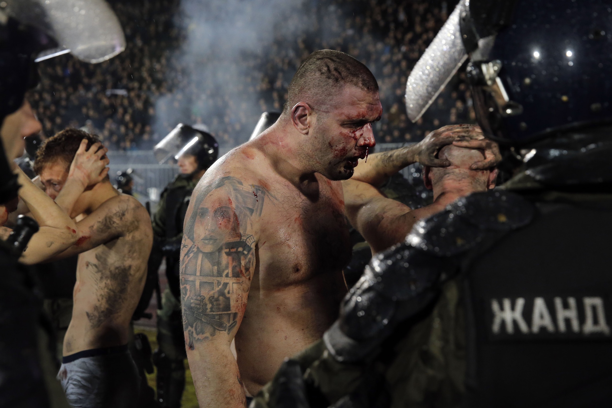 TOPSHOT - Policemen arrest Partizan Belgrade's hooligans after clashes between two groups of Partizan Belgrade's supporters during the Serbian Superleague derby football match between Partizan Belgrade and Crvena Zvezda (Red Star), on December 13, 2017 in