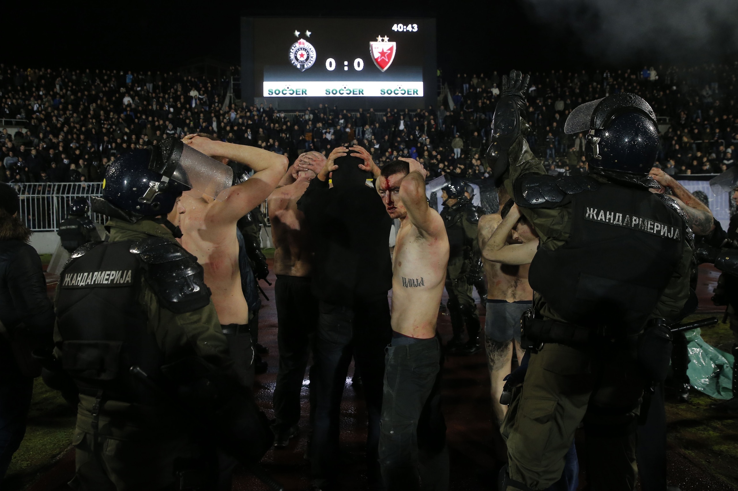 TOPSHOT - Policemen arrest Partizan Belgrade's hooligans after clashes between two groups of Partizan Belgrade's supporters during the Serbian Superleague derby football match between Partizan Belgrade and Crvena Zvezda (Red Star), on December 13, 2017 in