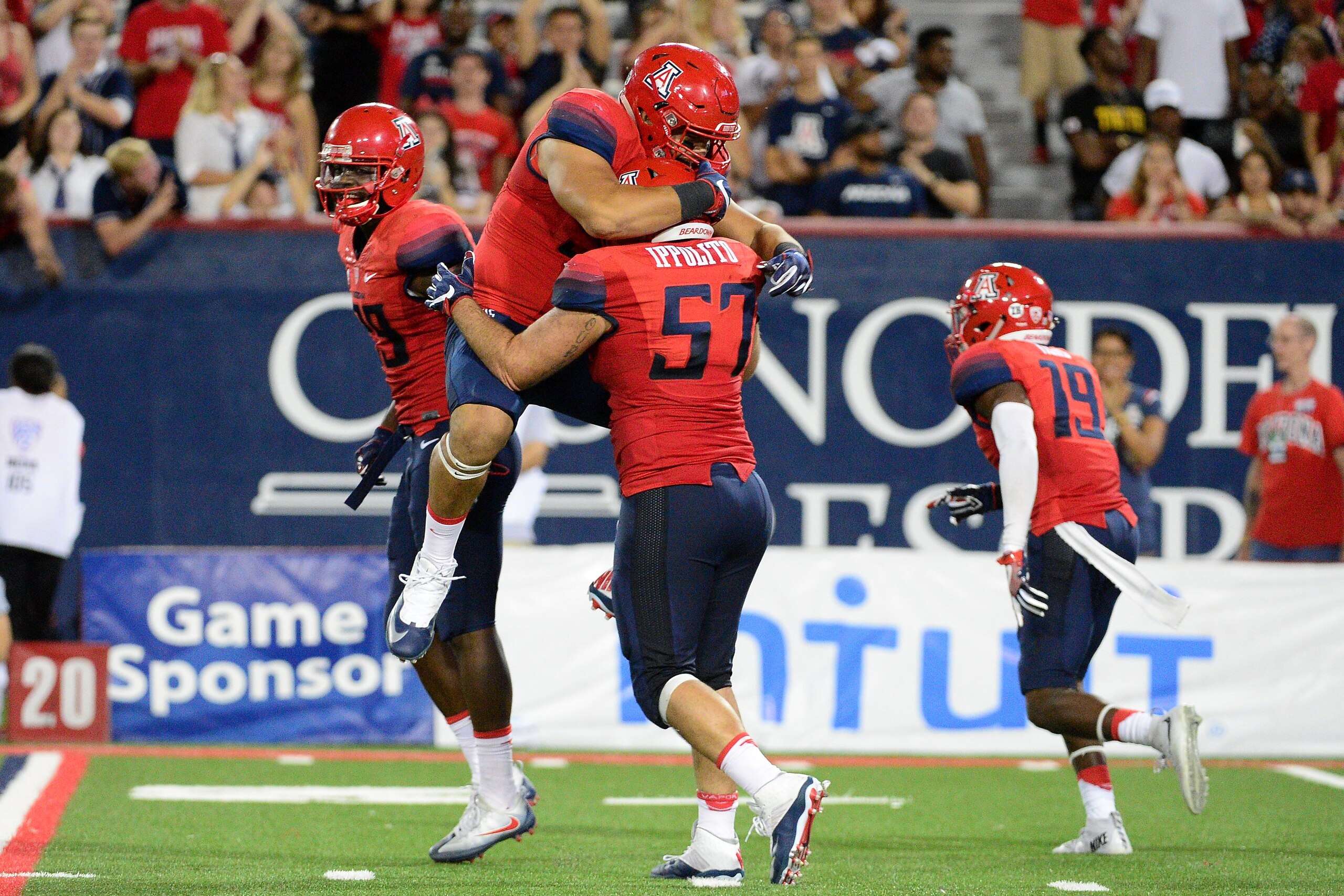 TUCSON, AZ - SEPTEMBER 10:  Defensive lineman Sani Fuimaono #99 of the Arizona Wildcats jumps on linebacker Cody Ippolito #57 after Arizona forced a fumble in the third quarter of the game against the Grambling State Tigers at Arizona Stadium on September