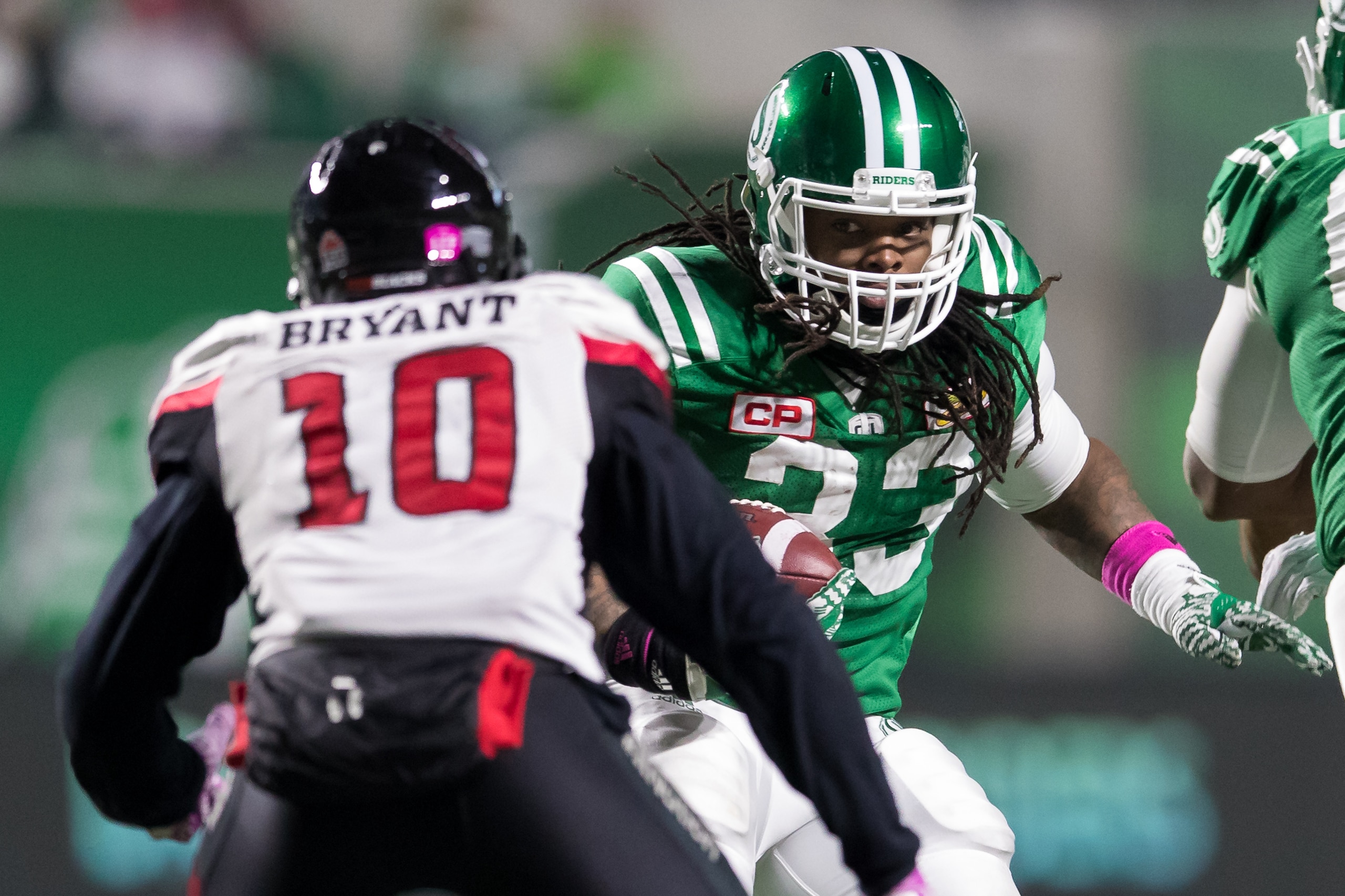 REGINA, SK - OCTOBER 13: Trent Richardson #33 of the Saskatchewan Roughriders looks to avoid Serderius Bryant #10 of the Ottawa Redblacks during a run in the first of the game between the Ottawa Redblacks and Saskatchewan Roughriders at Mosaic Stadium on 