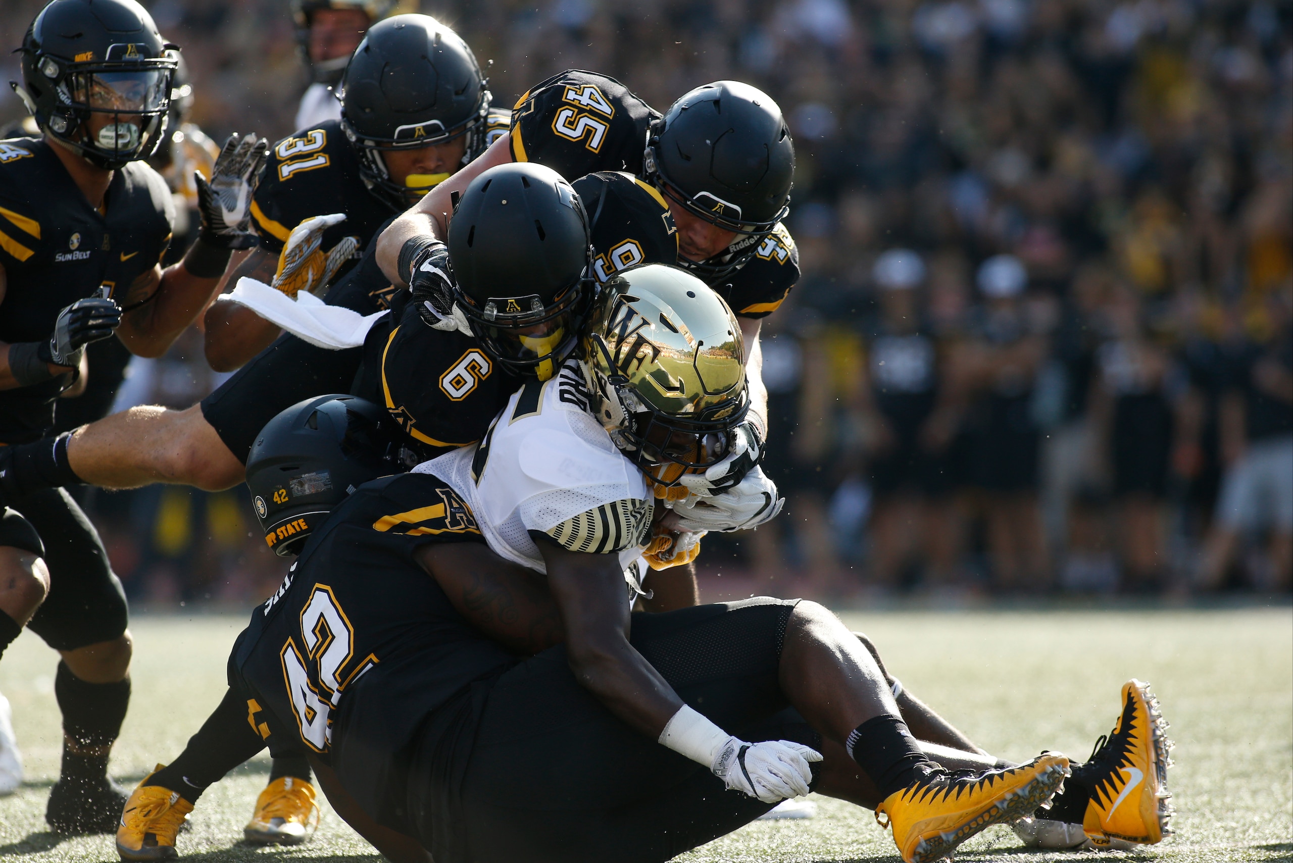 BOONE, NC - SEPTEMBER 23:  Running back Arkeem Byrd #5 of the Wake Forest Demon Deacons is stopped by defensive back Desmond Franklin #6 of the Appalachian State Mountaineers, defensive lineman Antonious Sims #42 and linebacker Eric Boggs #45 during the s