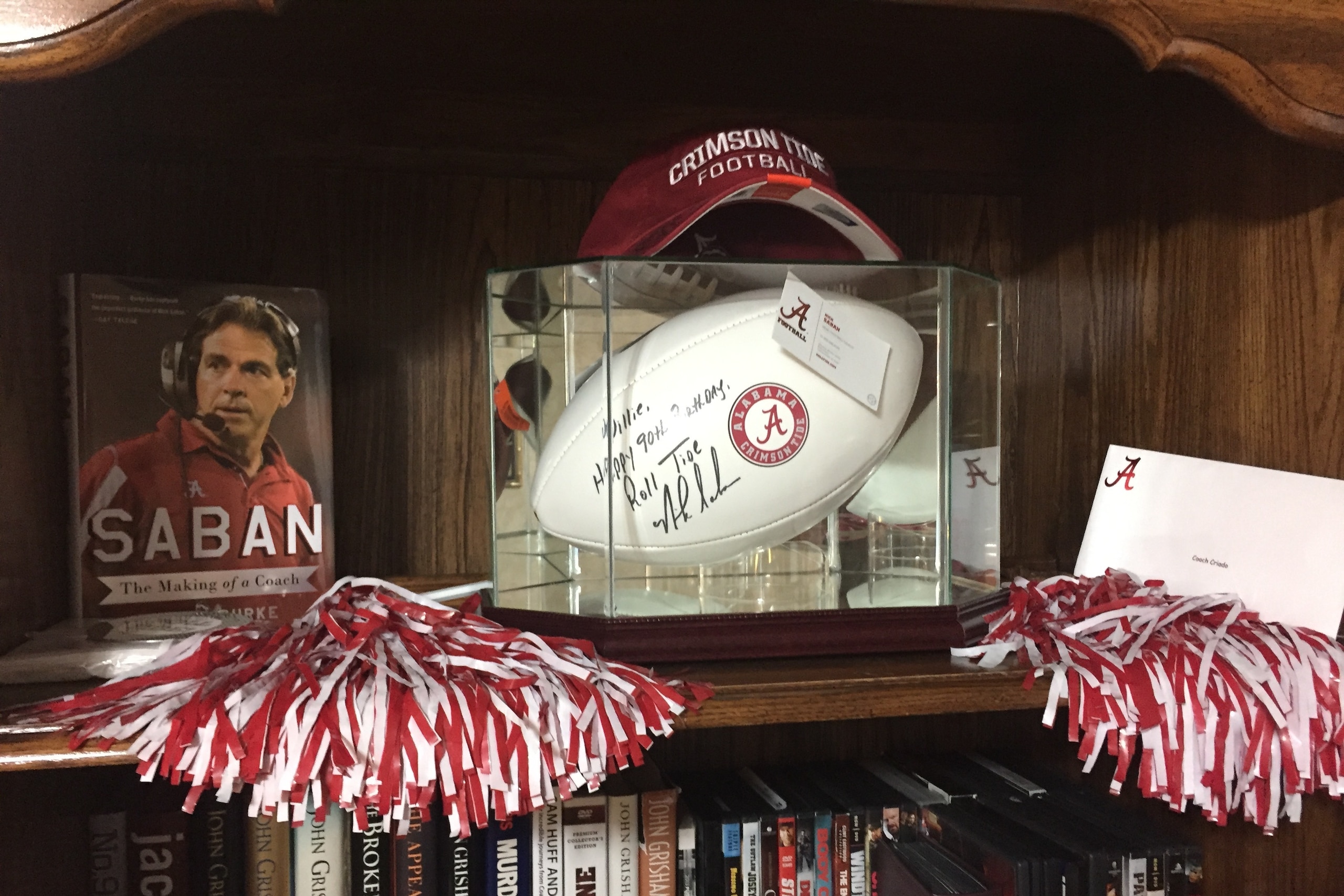 Willie Criado's bookshelf features Nick Saban memorabilia.