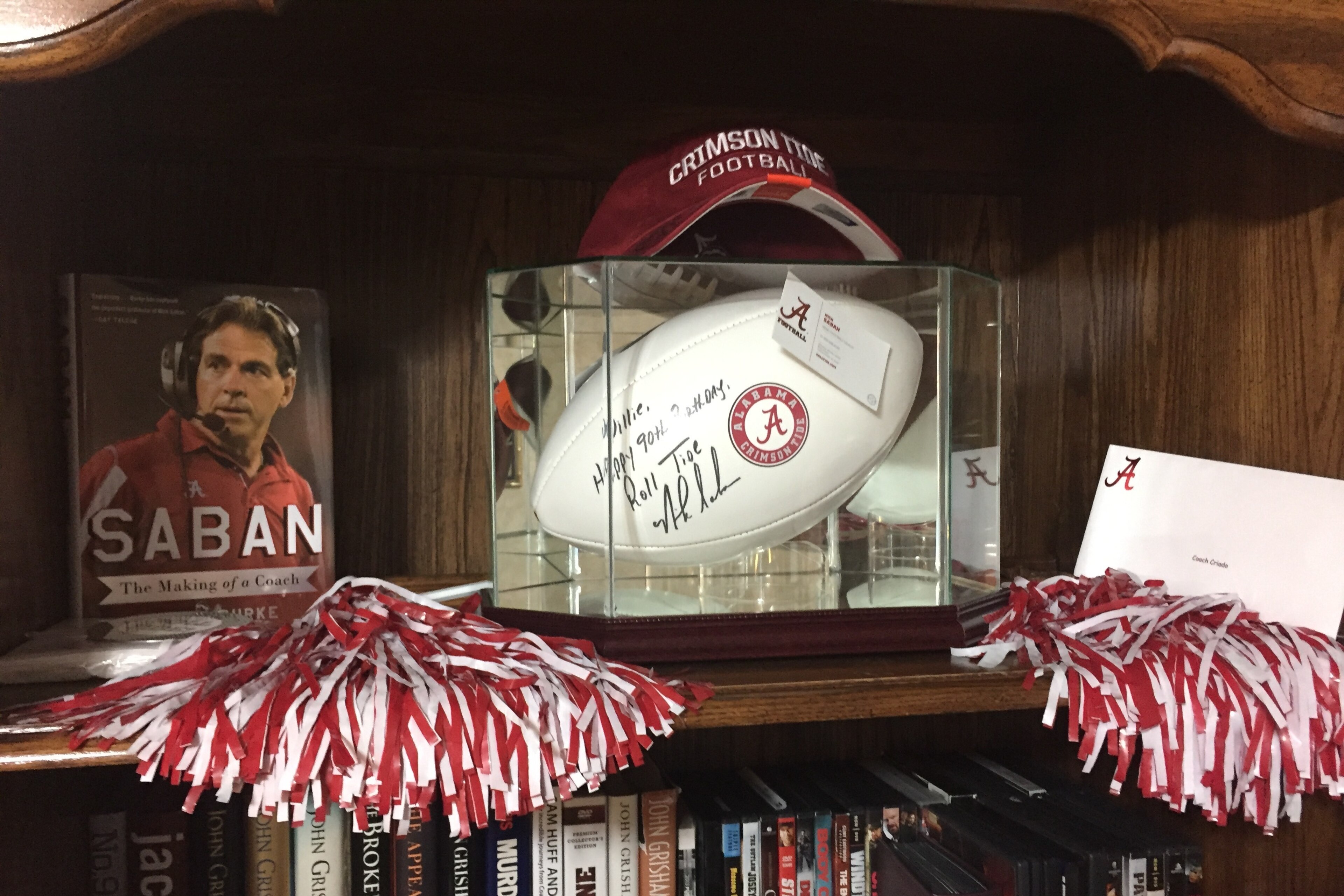 Willie Criado's bookshelf features Nick Saban memorabilia.