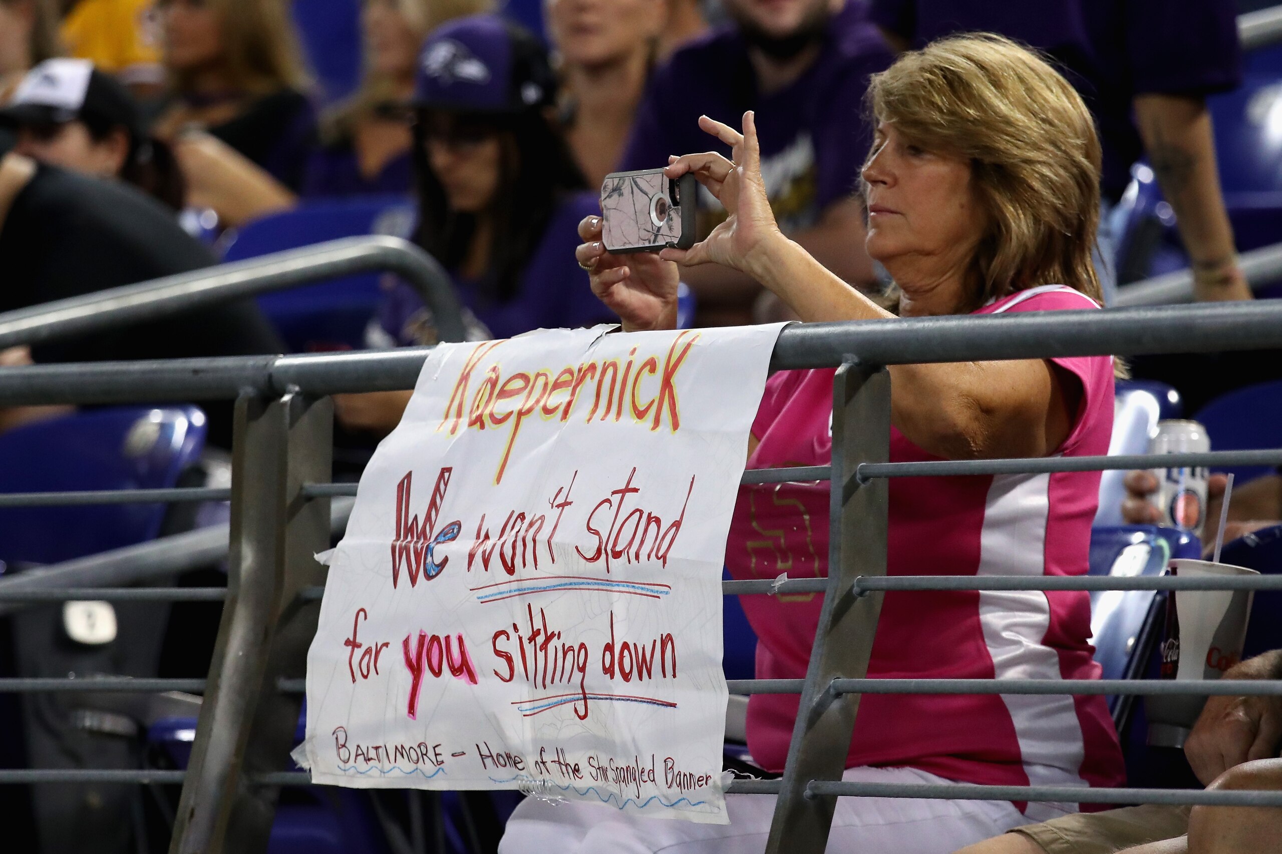 BALTIMORE, MD - AUGUST 10:  A fan uses her phone behind a sign referring to former San Francisco 49ers quarterback Colin Kaepernick in the second half of the Washington Redskins and Baltimore Ravens preseason game at M&T Bank Stadium on August 10, 2017 in
