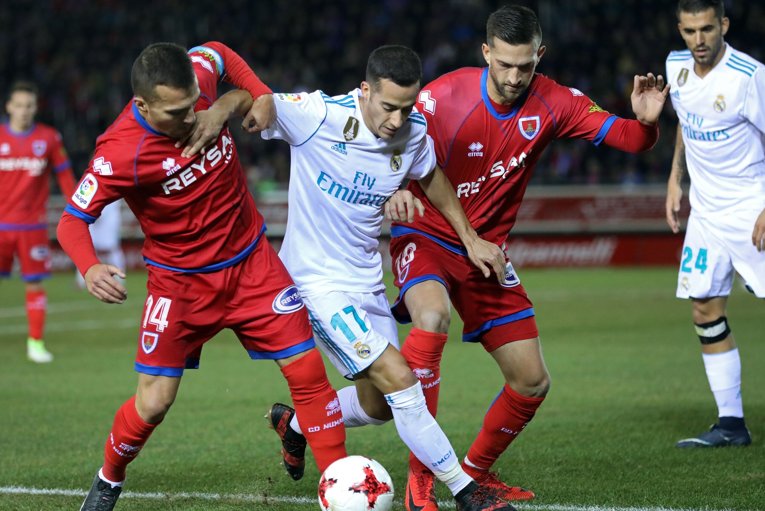 Numancia's midfielder Luis Valcarce (L) and Numancia's defender Grego (R) vie with Real Madrid's Spanish midfielder Lucas Vazquez (C) during the Spanish Copa del Rey (King's Cup) round of 16 first leg football match CD Numancia vs Real Madrid CF at Nuevo 