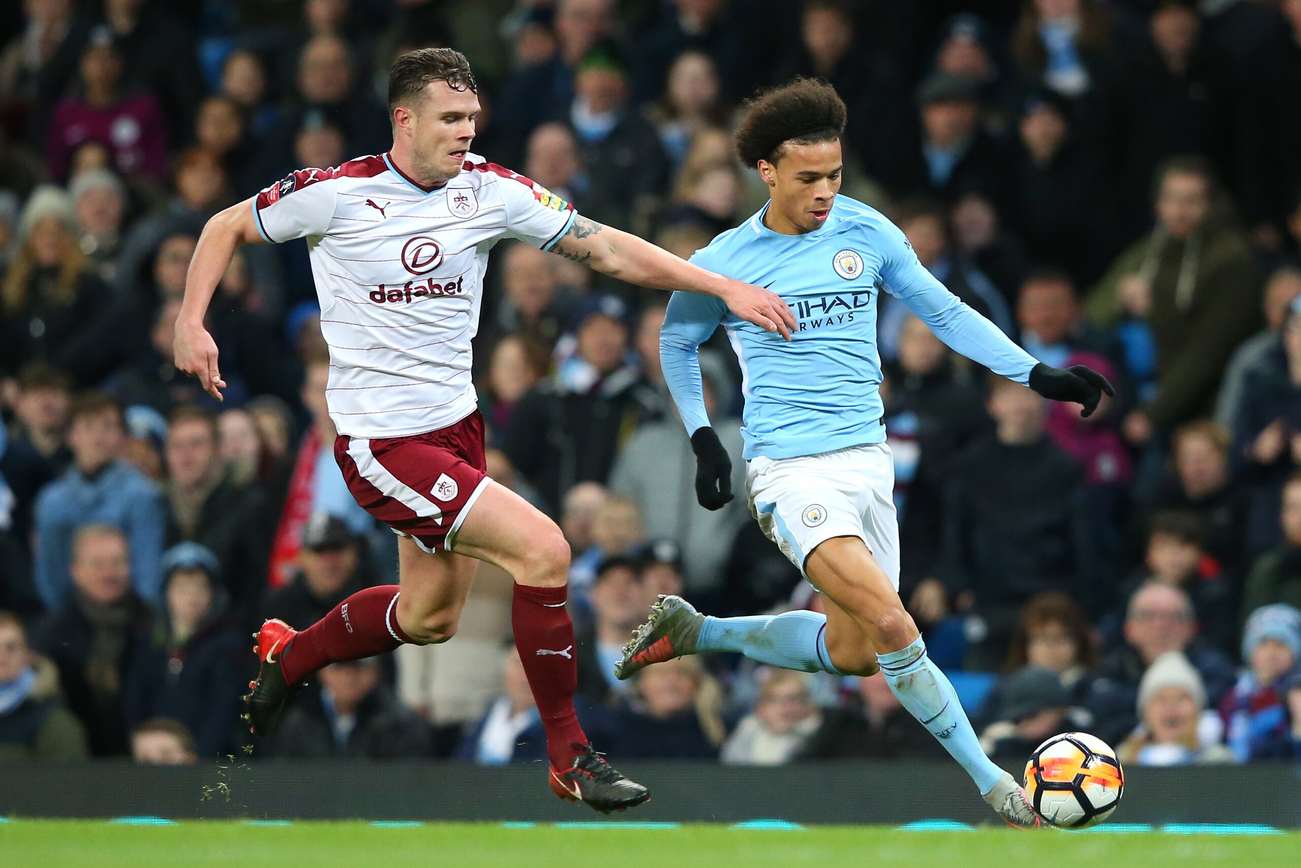 MANCHESTER, ENGLAND - JANUARY 06:  Leroy Sane of Manchester City runs with the ball under pressure from Kevin Long of Burnley during The Emirates FA Cup Third Round match between Manchester City and Burnley at Etihad Stadium on January 6, 2018 in Manchest