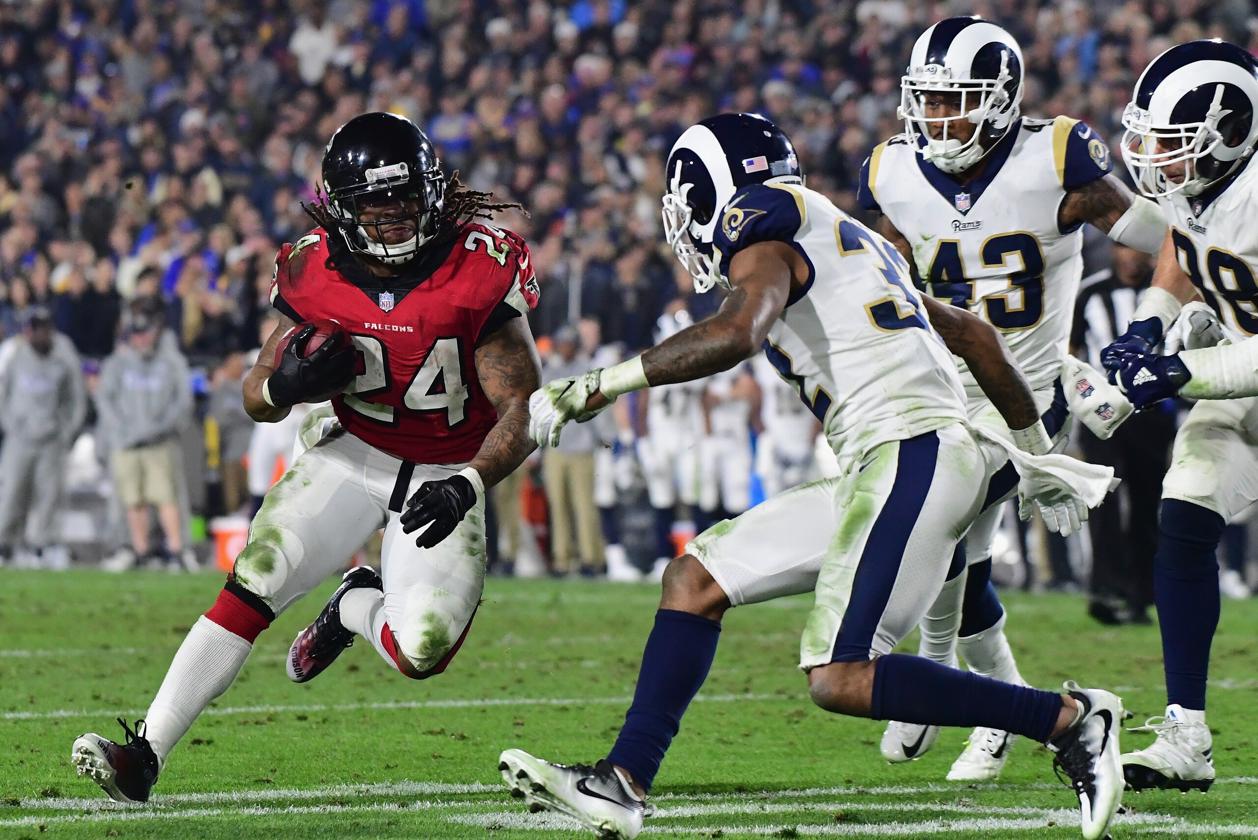 LOS ANGELES, CA - JANUARY 06:  Running back Devonta Freeman #24 of the Atlanta Falcons carries the ball in front of cornerback Troy Hill #32 of the Los Angeles Rams during the fourth quarter of the NFC Wild Card Playoff game at Los Angeles Coliseum on Jan