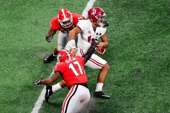 ATLANTA, GA - JANUARY 08: Tua Tagovailoa #13 of the Alabama Crimson Tide runs the ball against Davin Bellamy #17 and D'Andre Walker #15 of the Georgia Bulldogs during the third quarter in the CFP National Championship presented by AT&T at Mercedes-Benz St